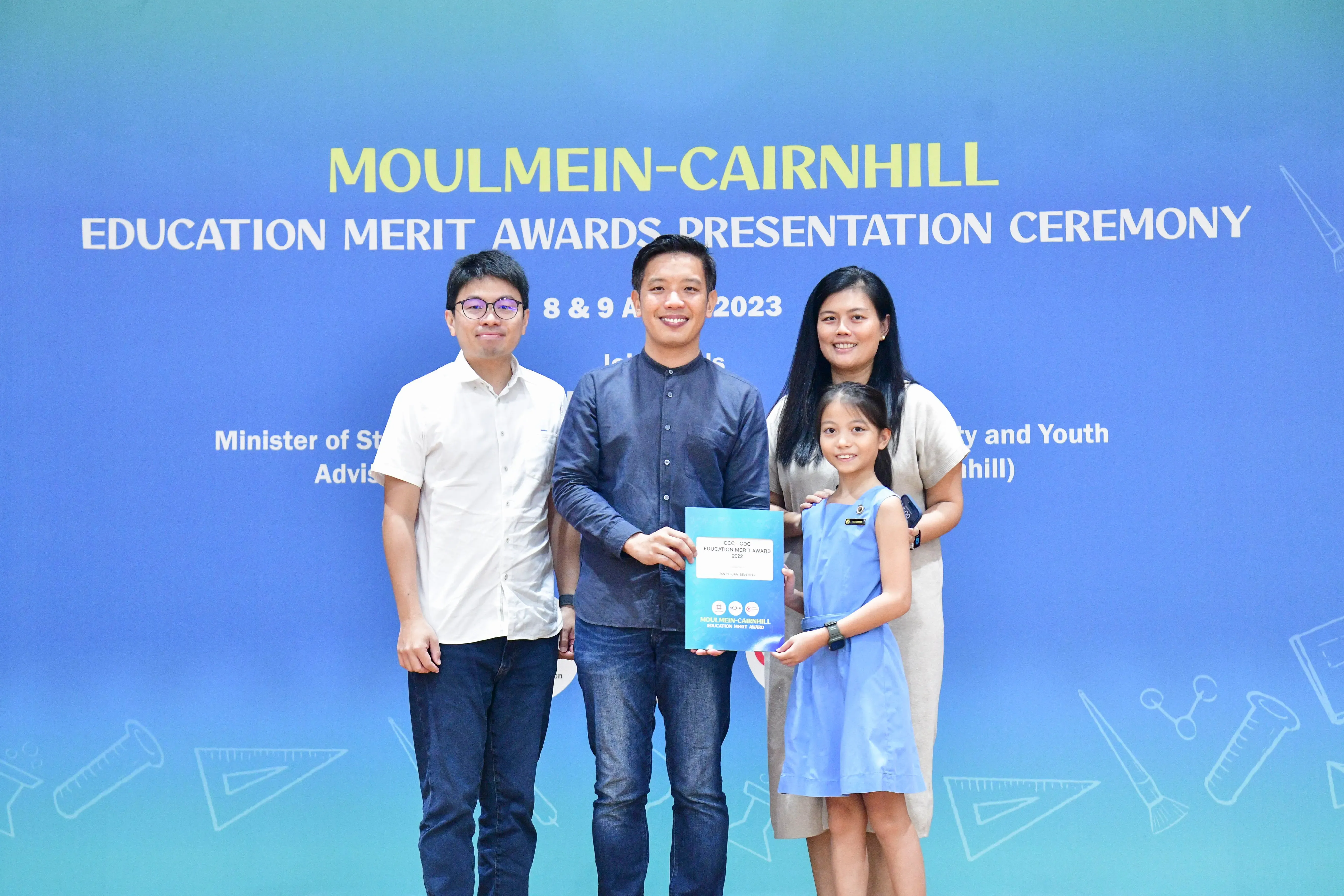 Three adults and a young girl hold a certificate at the Moulmein-Cairnhill Education Merit Awards 2023.