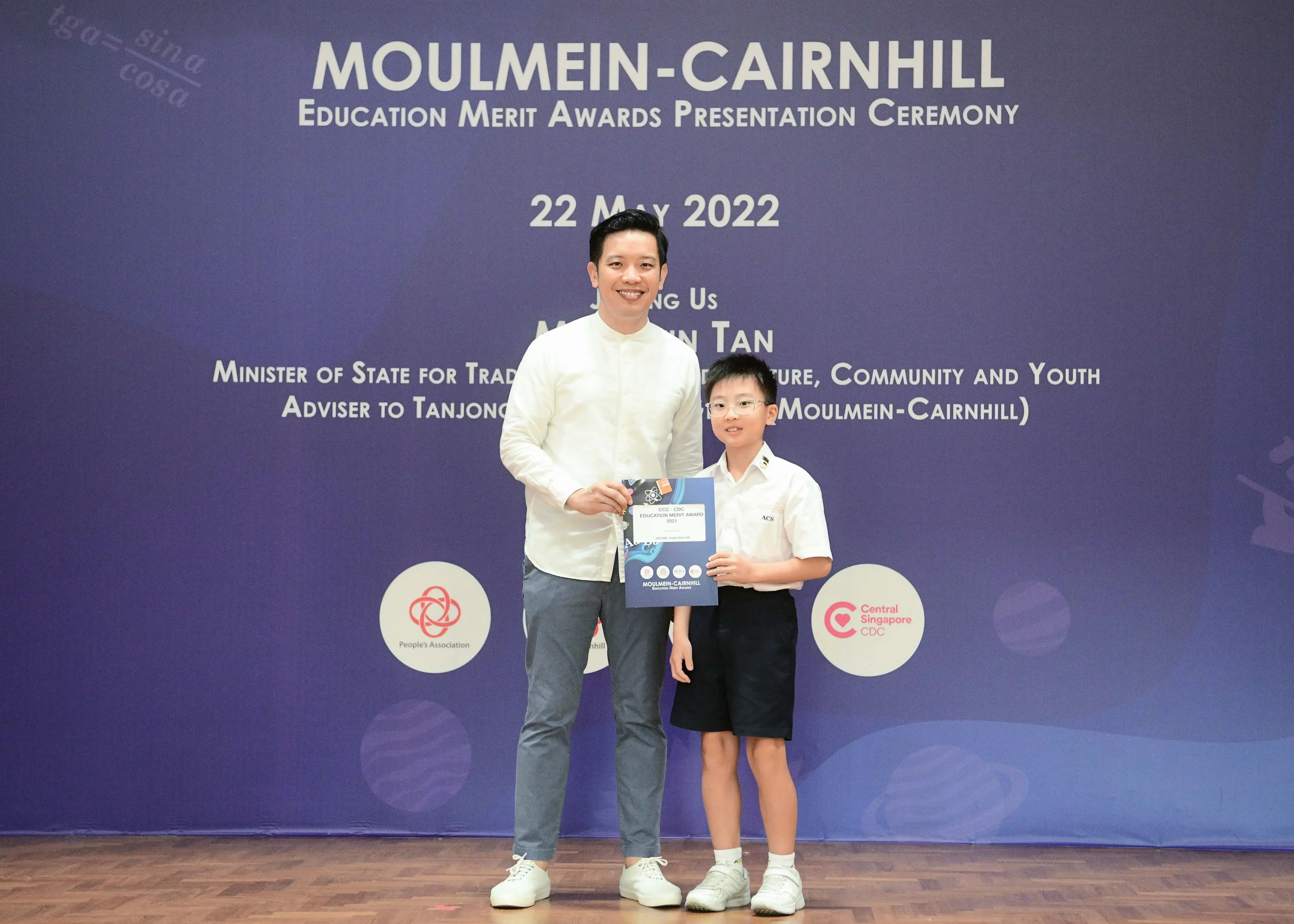 A man and a young boy hold a certificate at the Moulmein-Cairnhill Education Merit Awards Ceremony on 22 May 2022.
