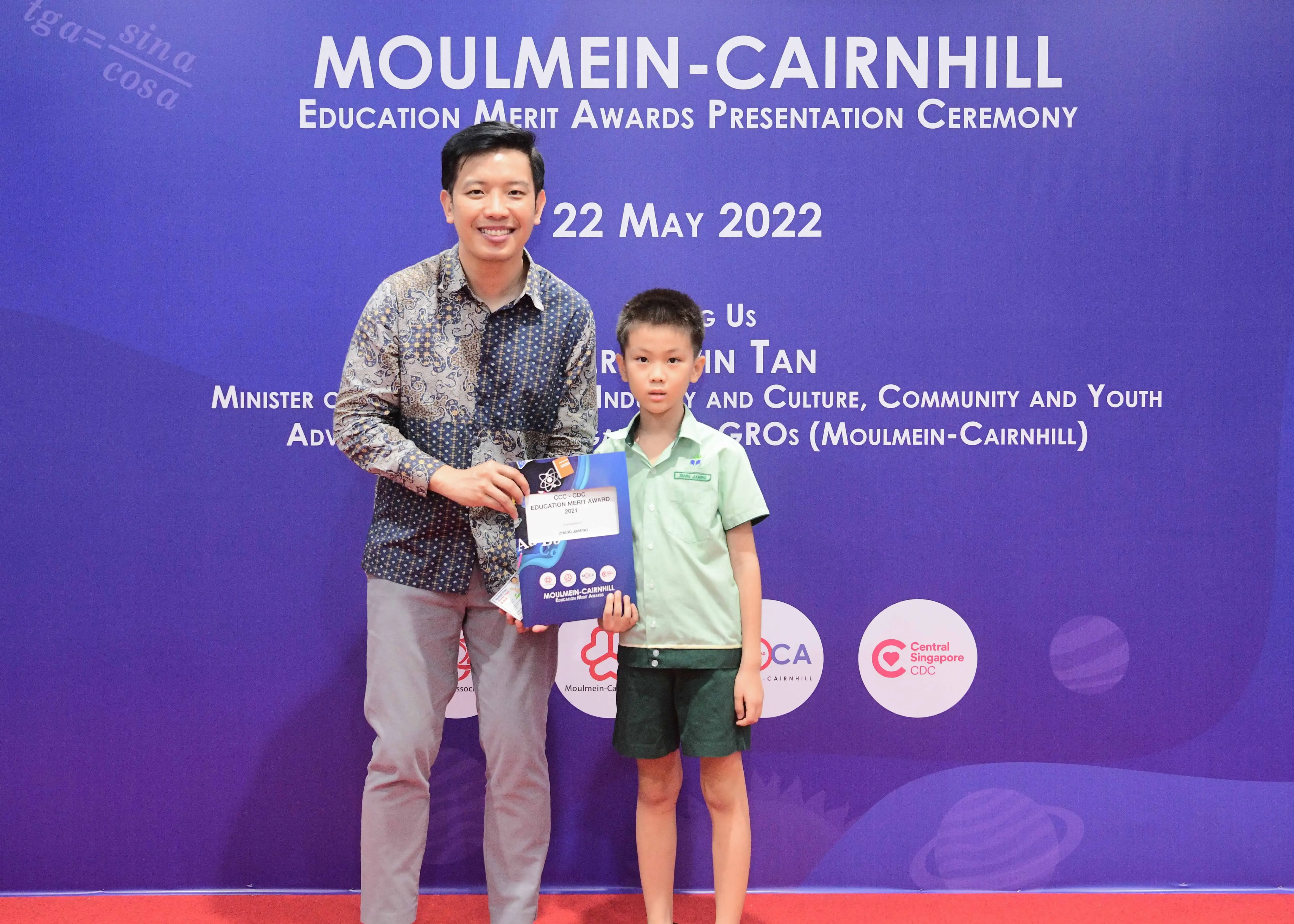 A man and a young boy pose holding an award at the Moulmein-Cairnhill Education Merit Awards on 22 May 2022.