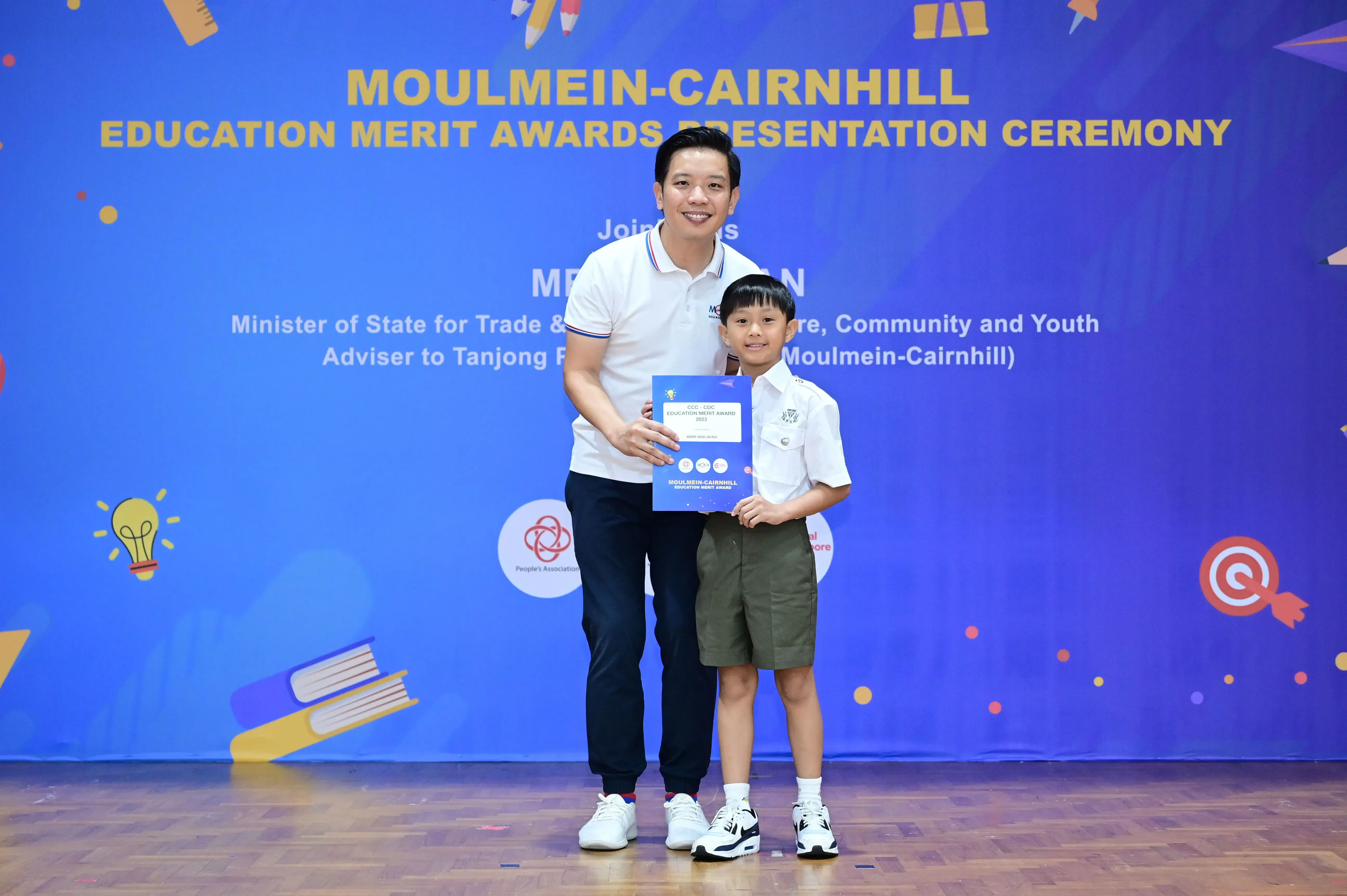 Man and young boy holding an award certificate at the Moulmein-Cairnhill Education Merit Awards Presentation Ceremony.