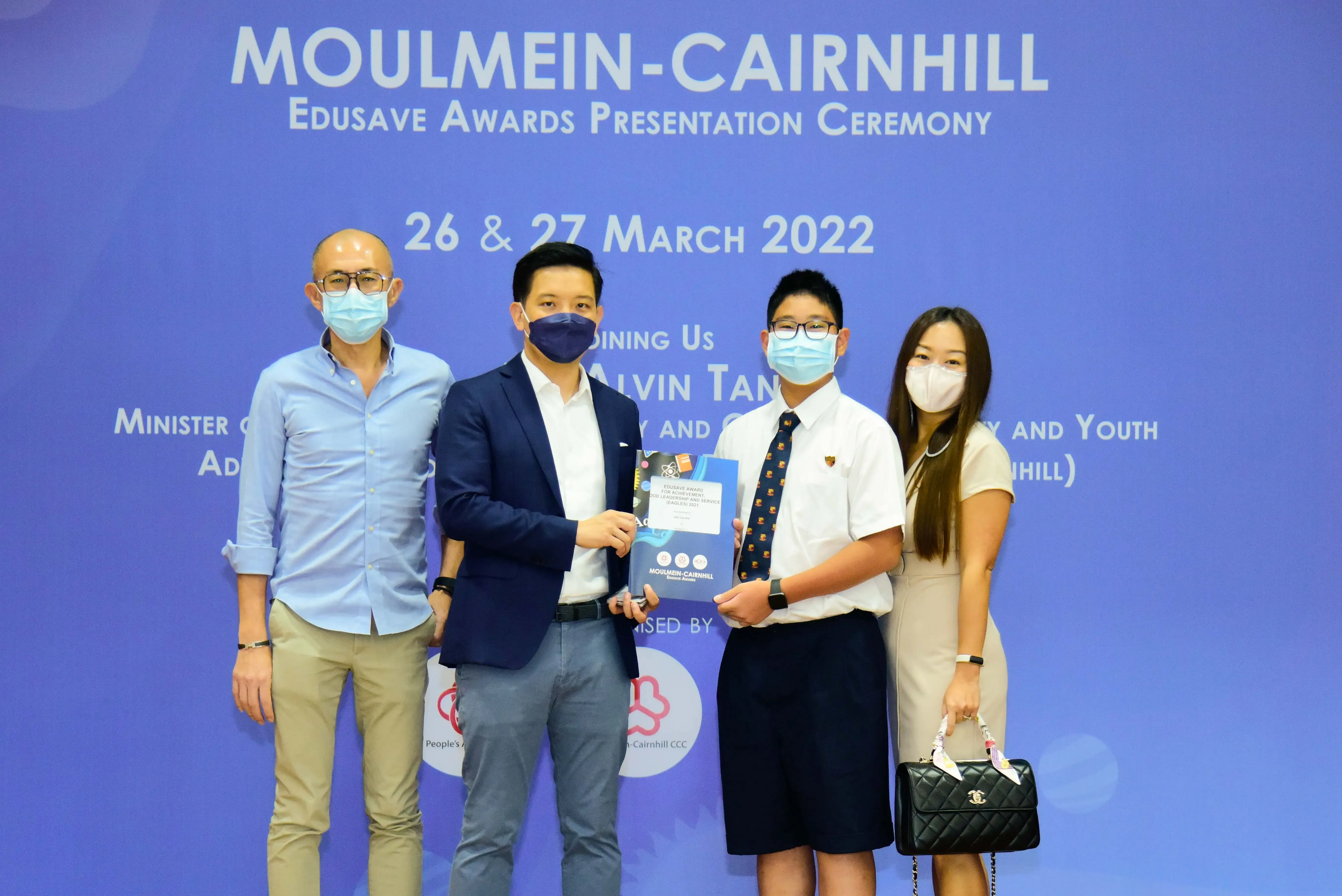 Four masked people pose at the Moulmein-Cairnhill Edusave Awards Presentation Ceremony on 26-27 March 2022.