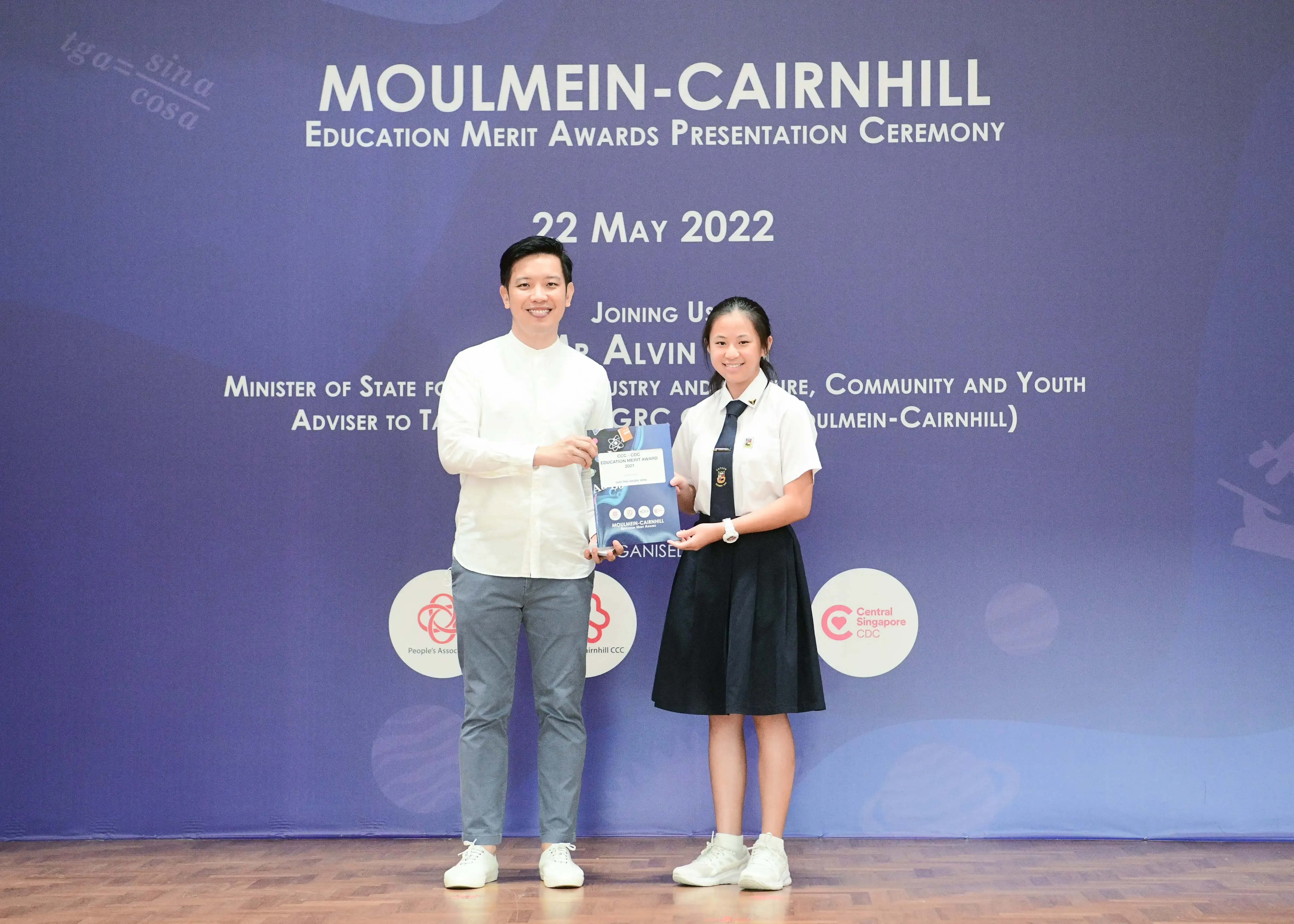 A man and a school girl hold an award together at the Moulmein-Cairnhill Education Merit Awards on 22 May 2022.