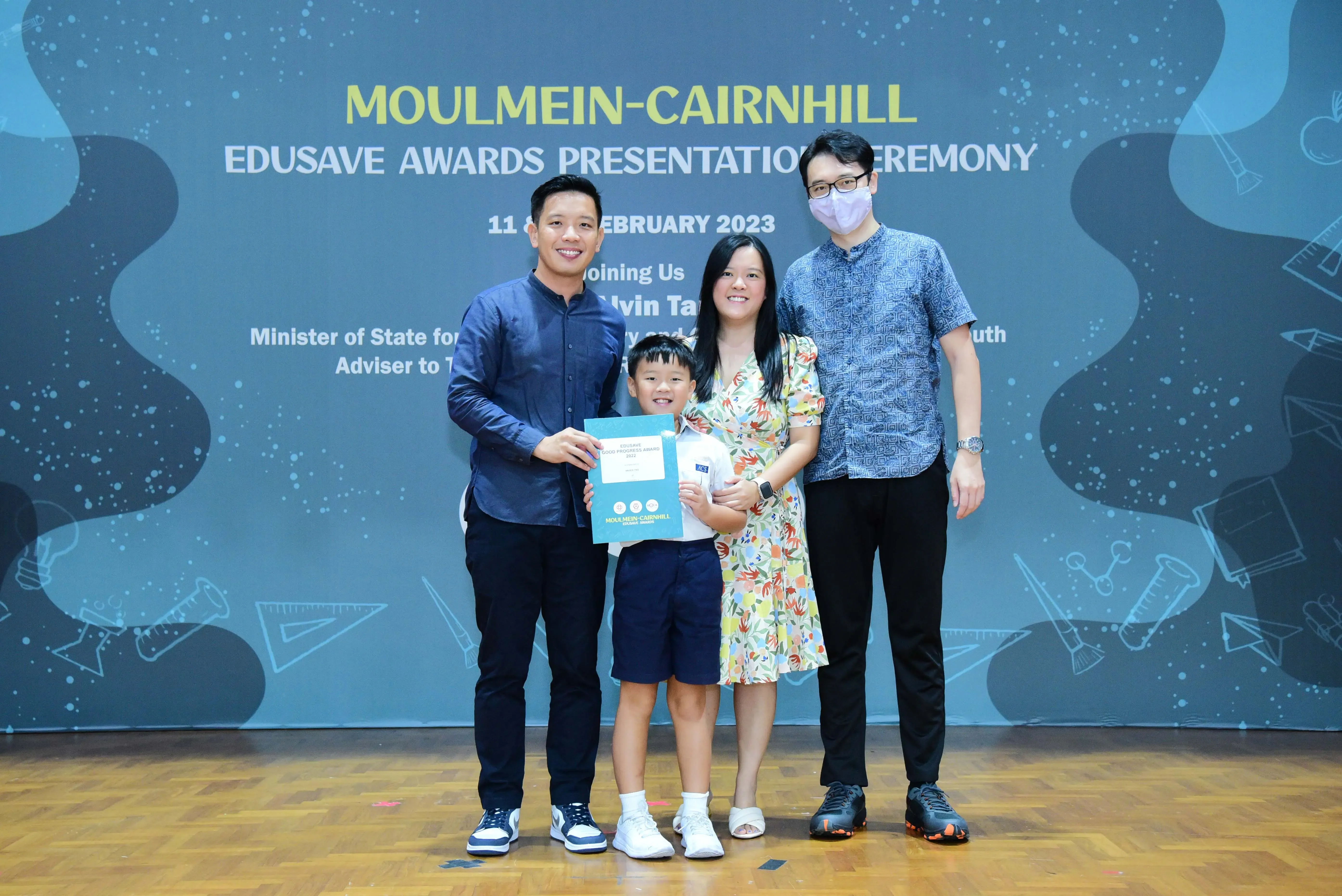 Three adults and a young boy holding a certificate pose at the Moulmein-Cairnhill Edusave Awards Ceremony 2023.