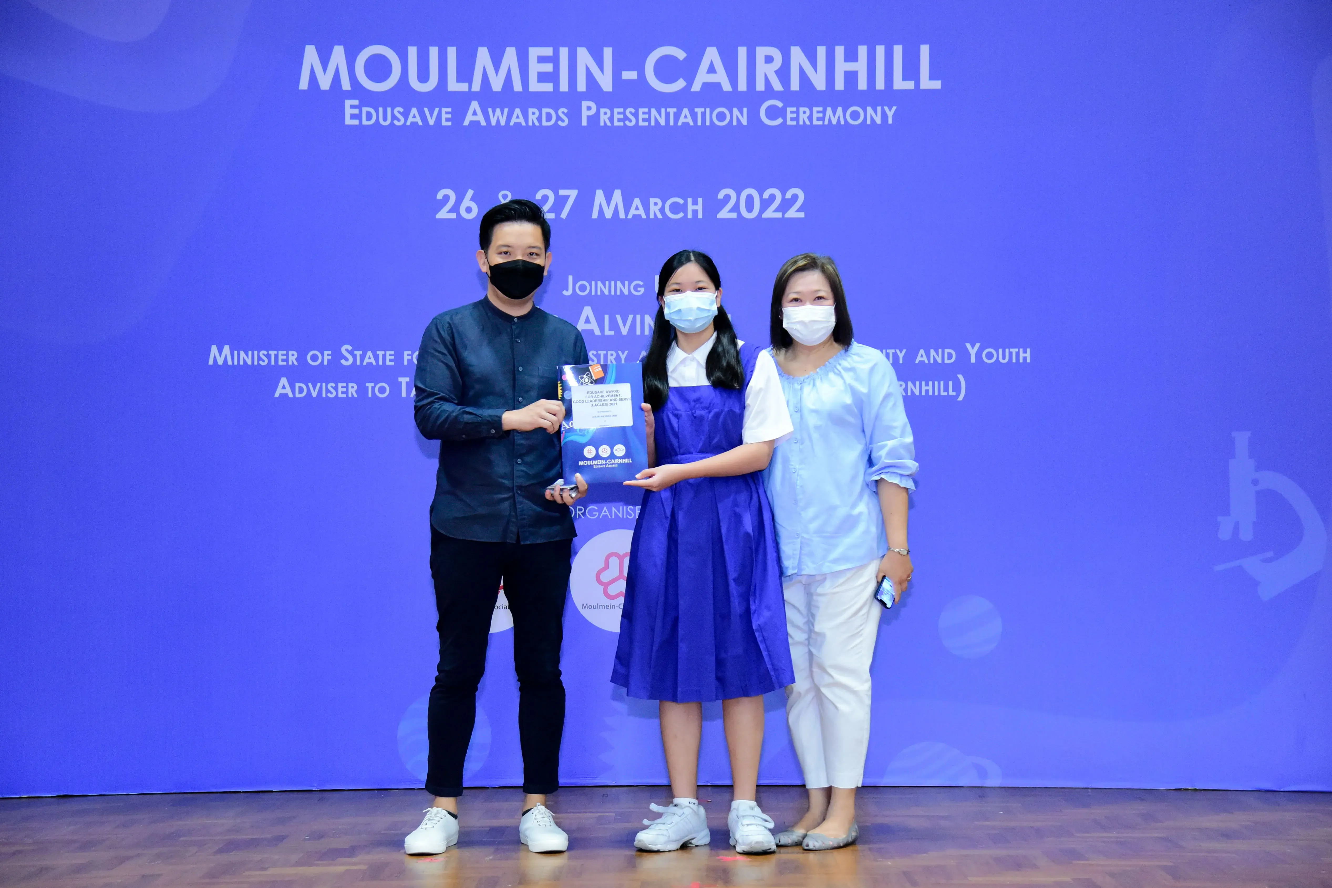 Three masked people pose at the Moulmein-Cairnhill Edusave Awards Presentation Ceremony on 26-27 March 2022.