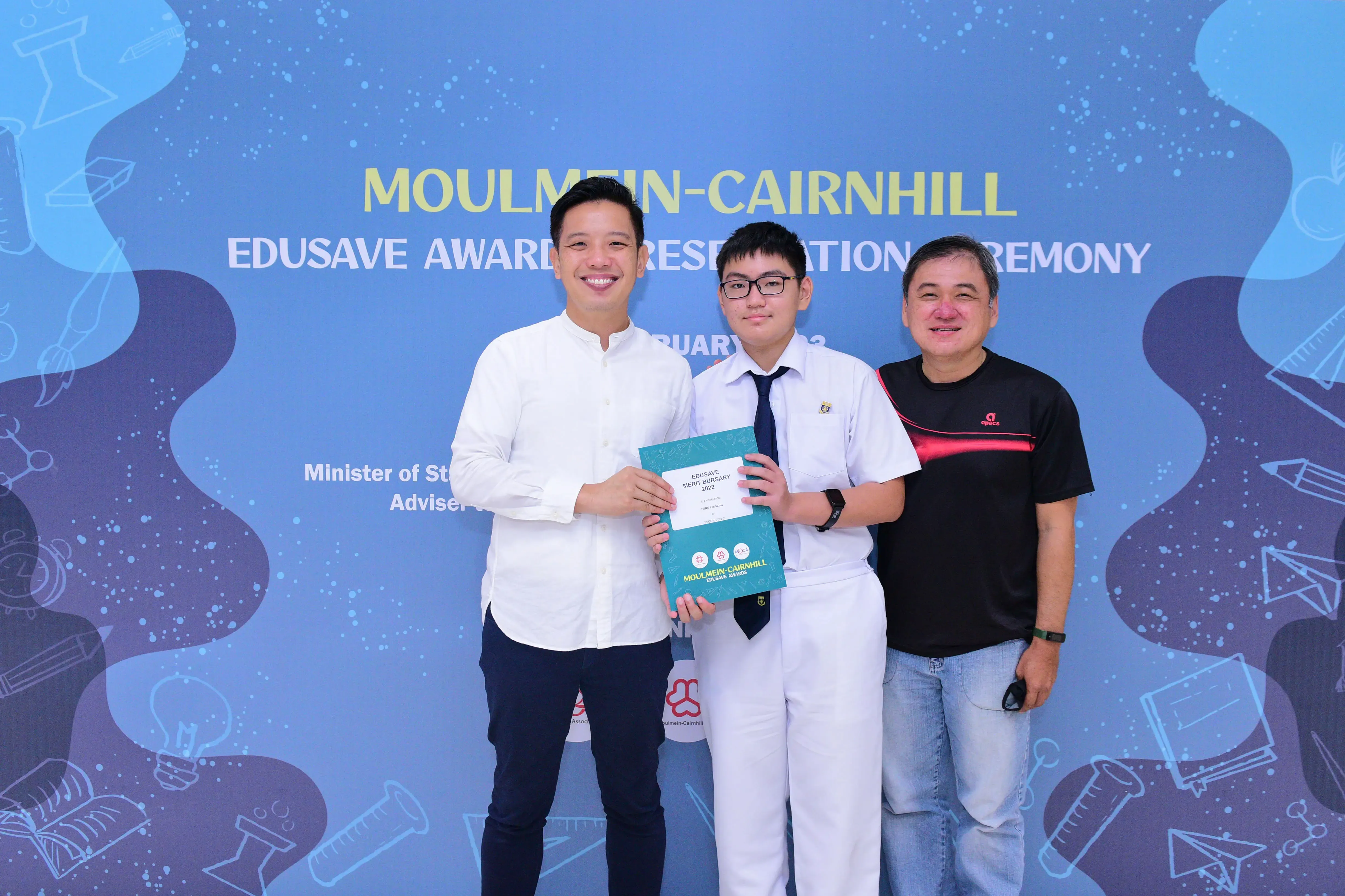 Three people pose at the Moulmein-Cairnhill Edusave Awards Presentation Ceremony, with a student holding a certificate.