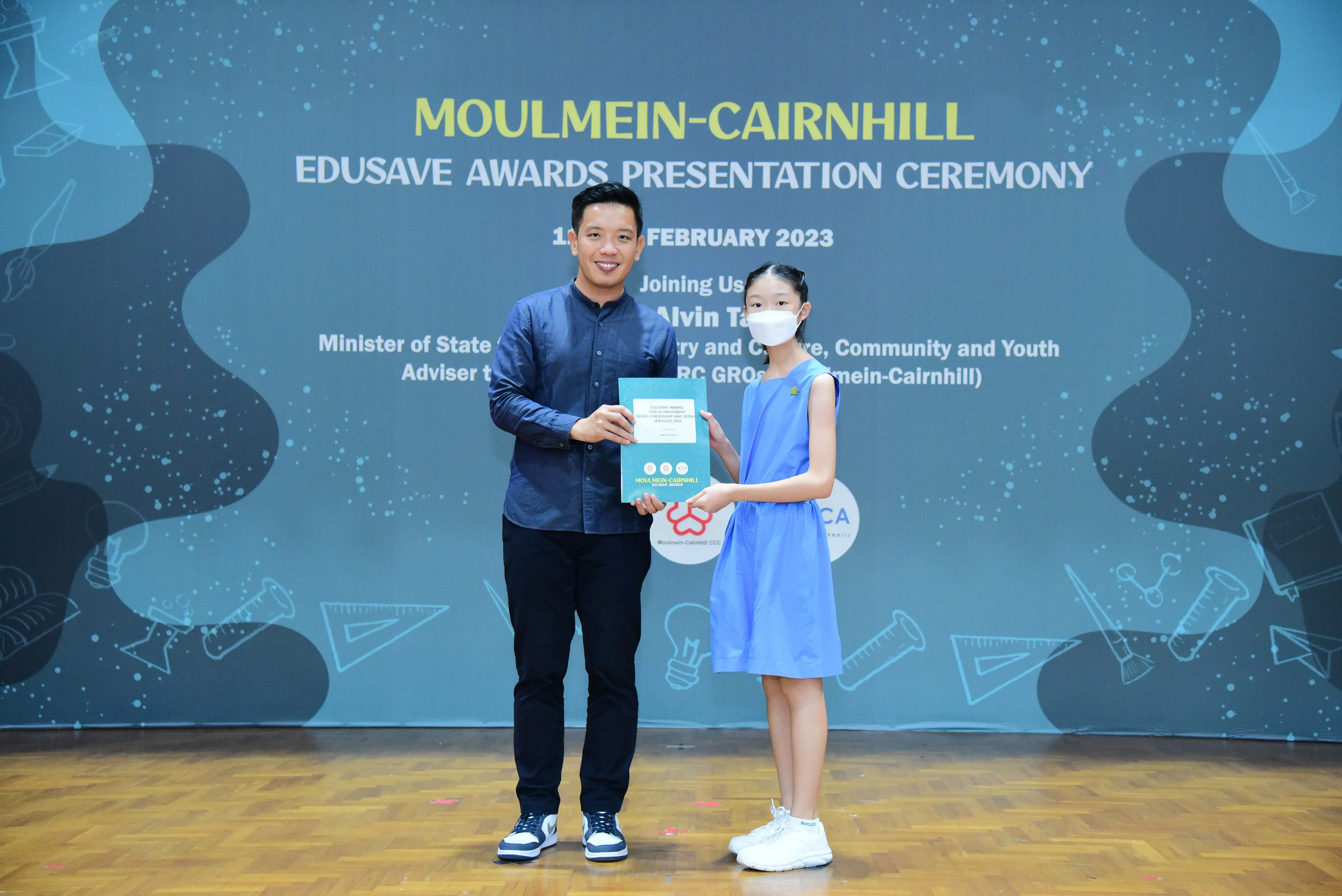 A man and a young girl hold an award certificate at the Moulmein-Cairnhill Edusave Awards Ceremony, February 2023.