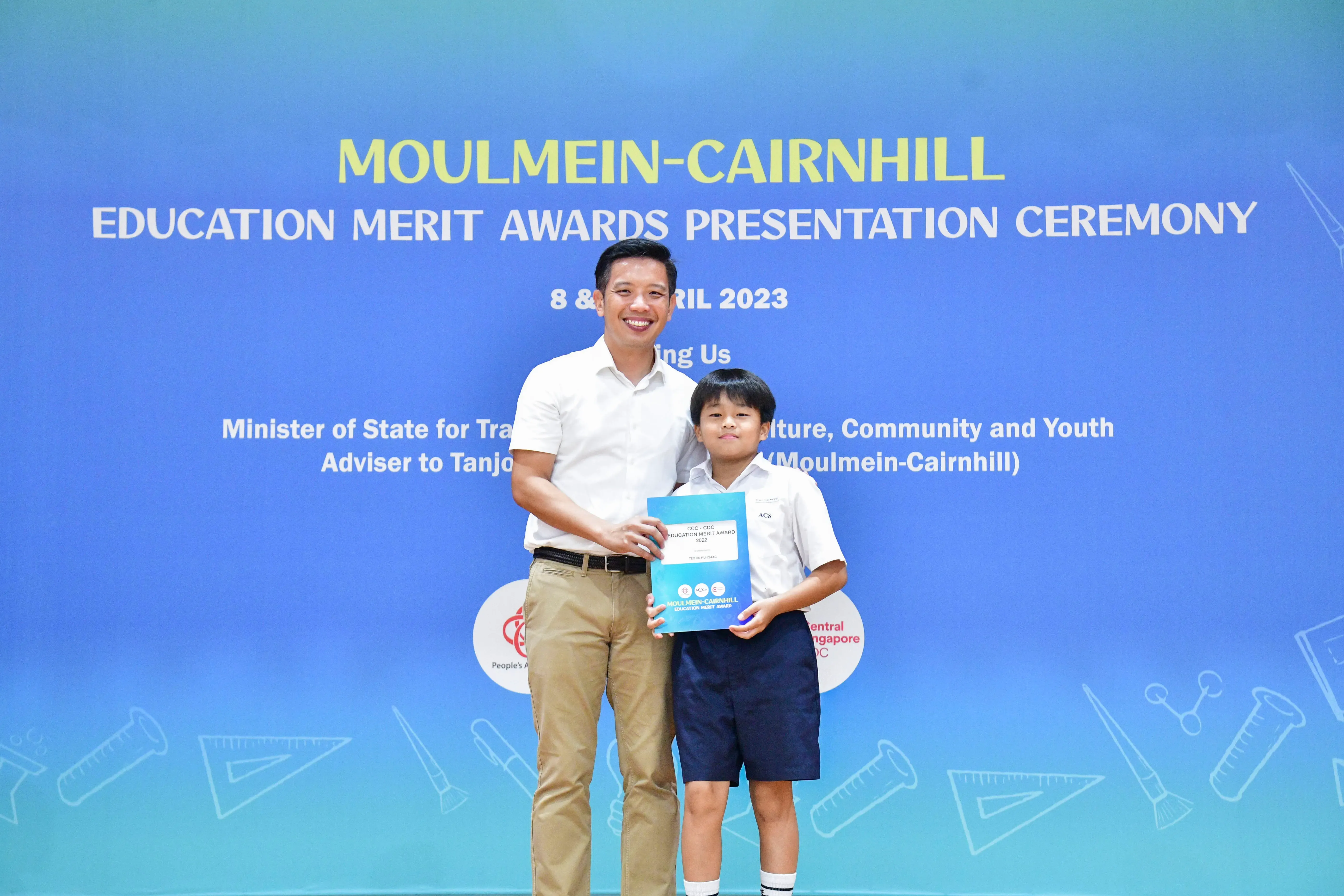 A man and a young boy pose together holding a certificate at the Moulmein-Cairnhill Education Merit Awards ceremony in 2023.