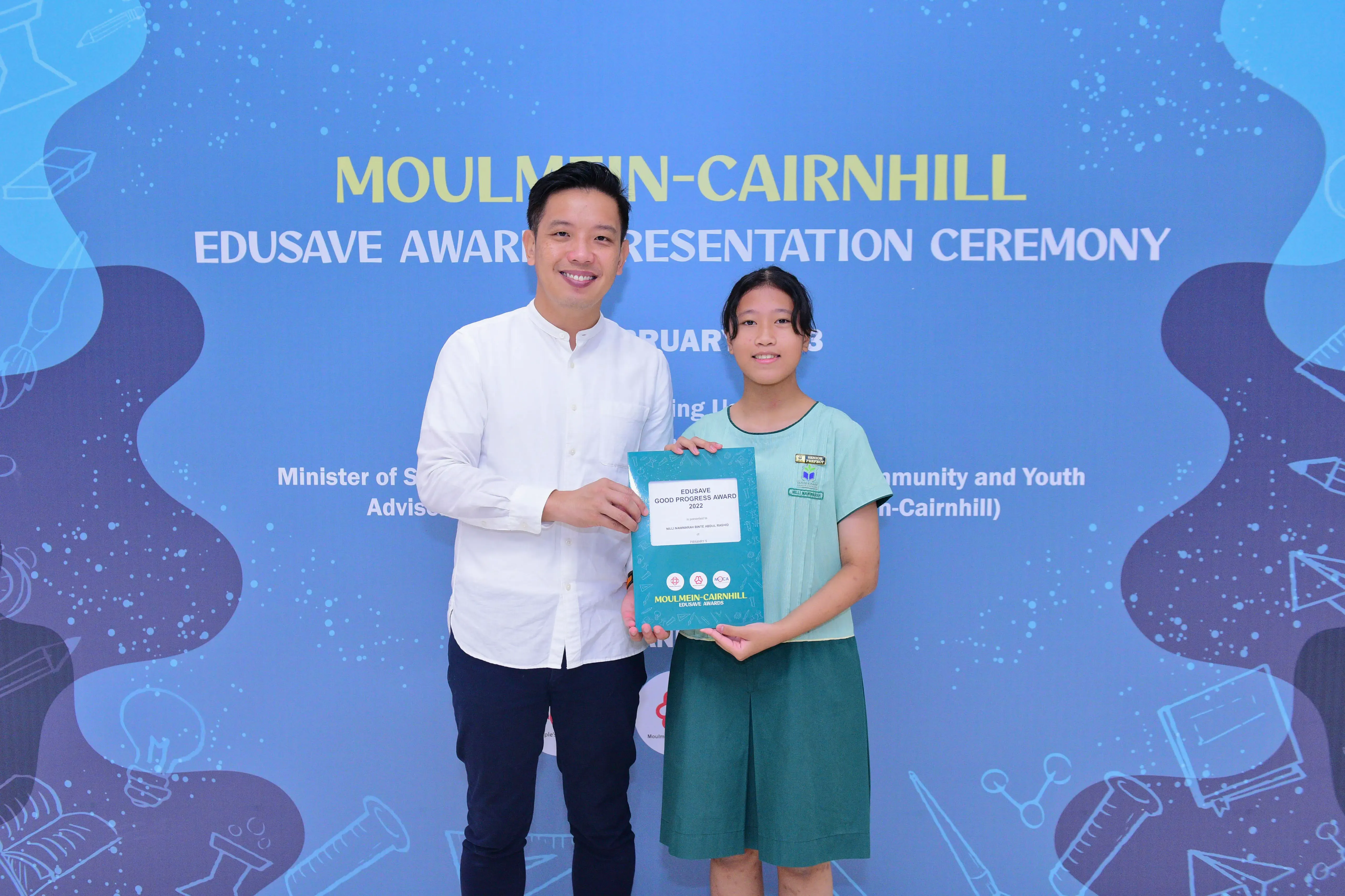 A man and a young girl hold an Edusave Good Progress Award certificate at the Moulmein-Cairnhill Award Ceremony.