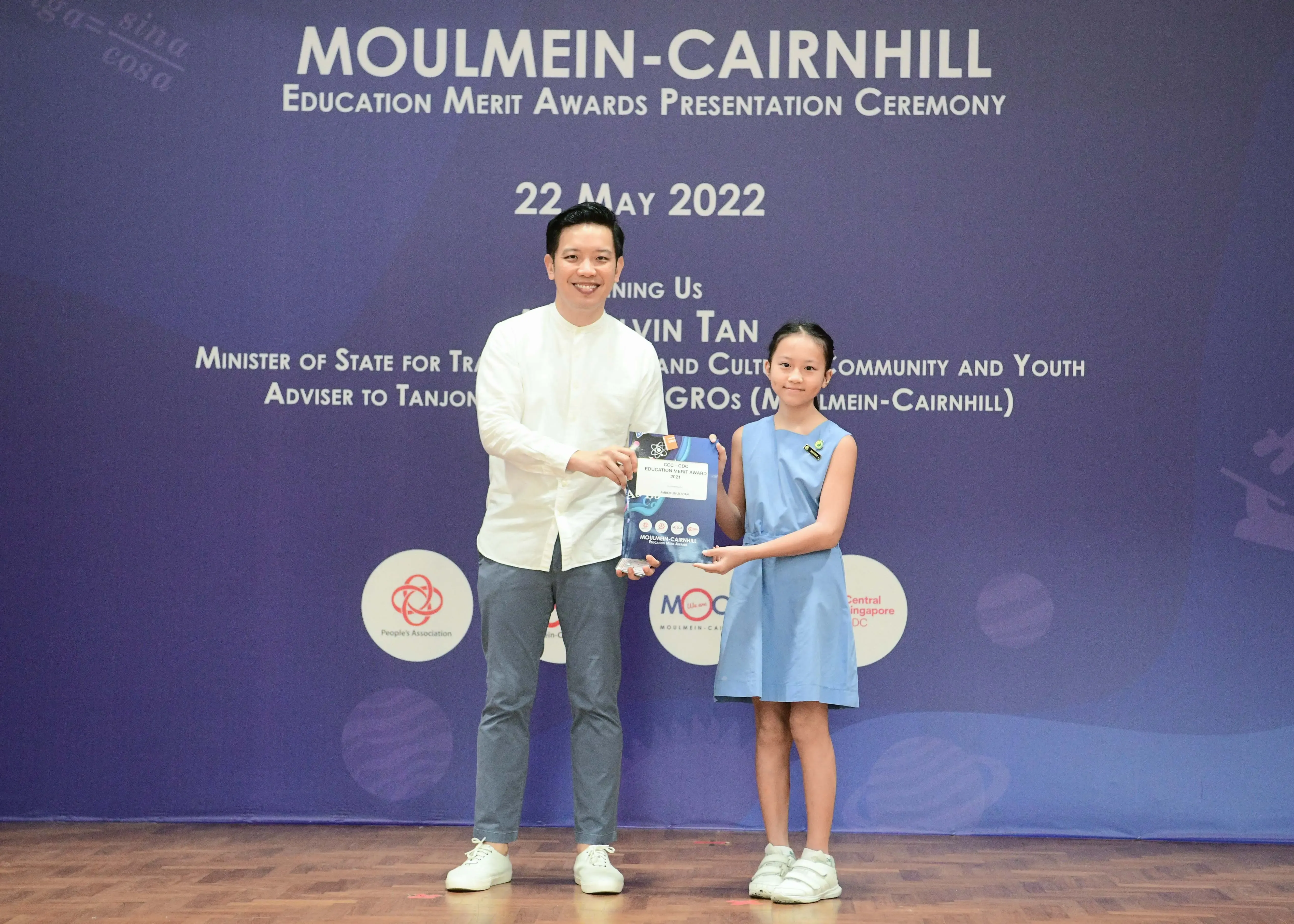 A man and a young girl hold an award together at the Moulmein-Cairnhill Education Merit Awards ceremony on 22 May 2022.