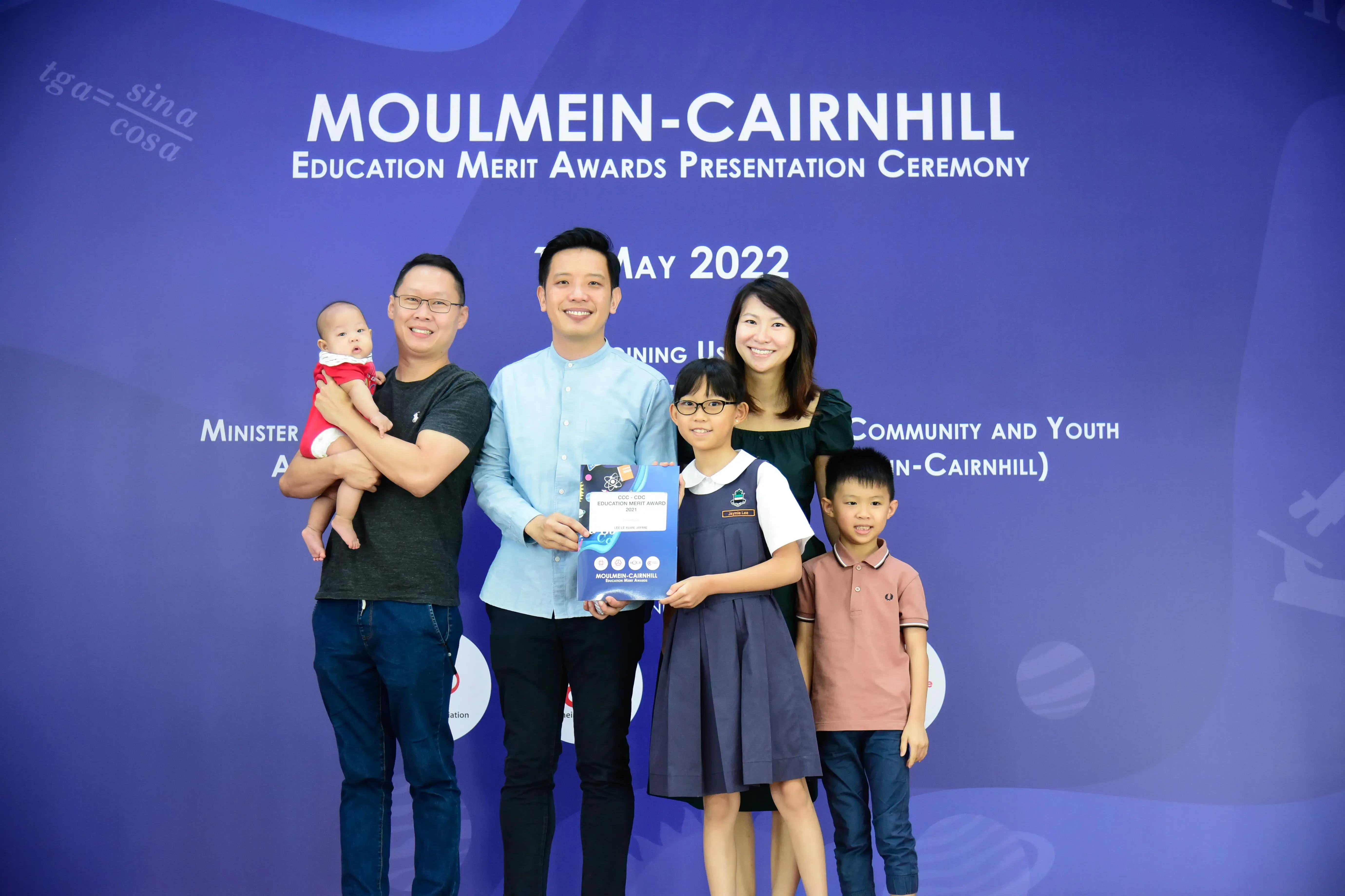 Five people pose at the Moulmein-Cairnhill Education Merit Awards Ceremony on May 2022, holding an award certificate.