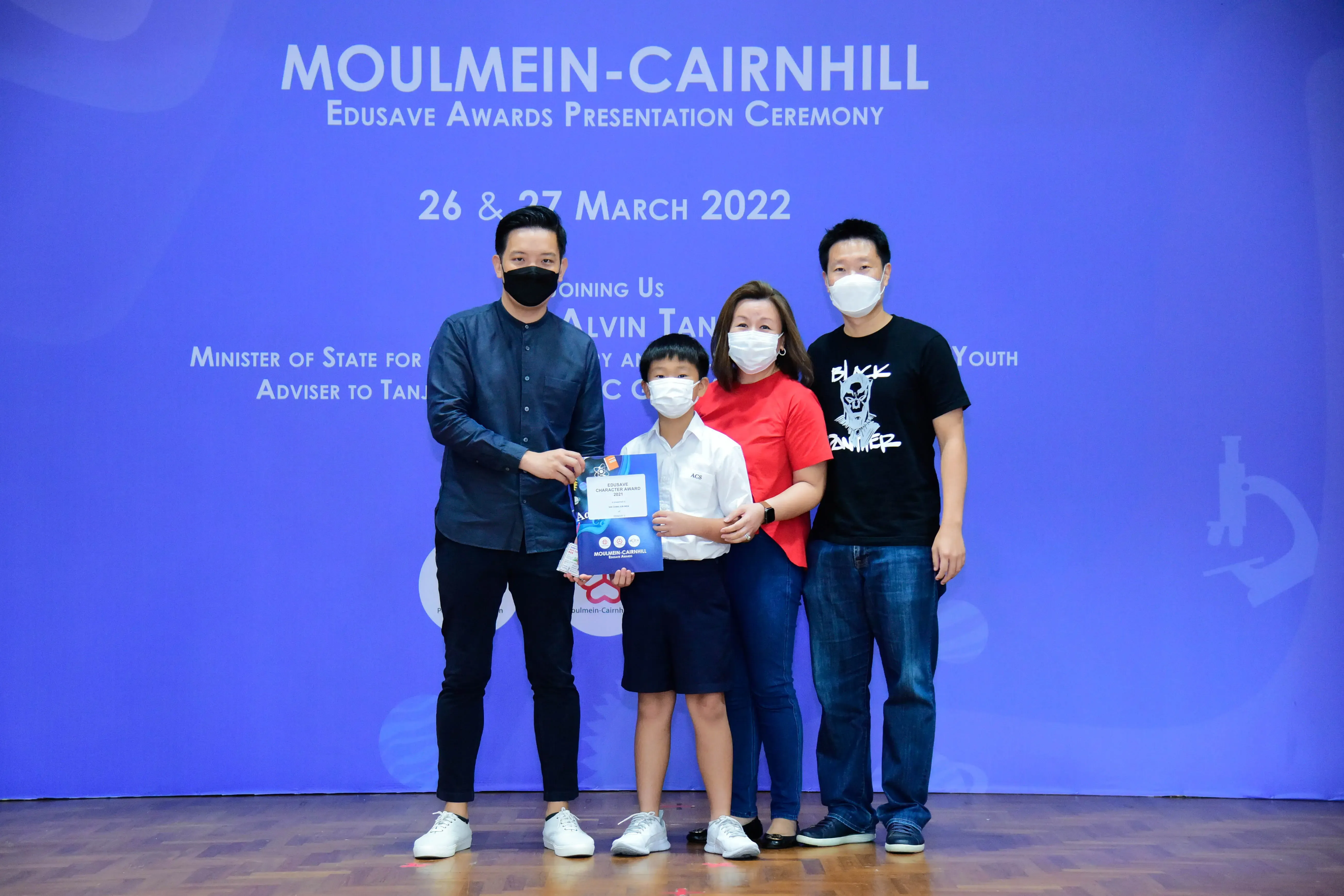 Four masked people pose at the Moulmein-Cairnhill Edusave Awards Presentation Ceremony on 26-27 March 2022.
