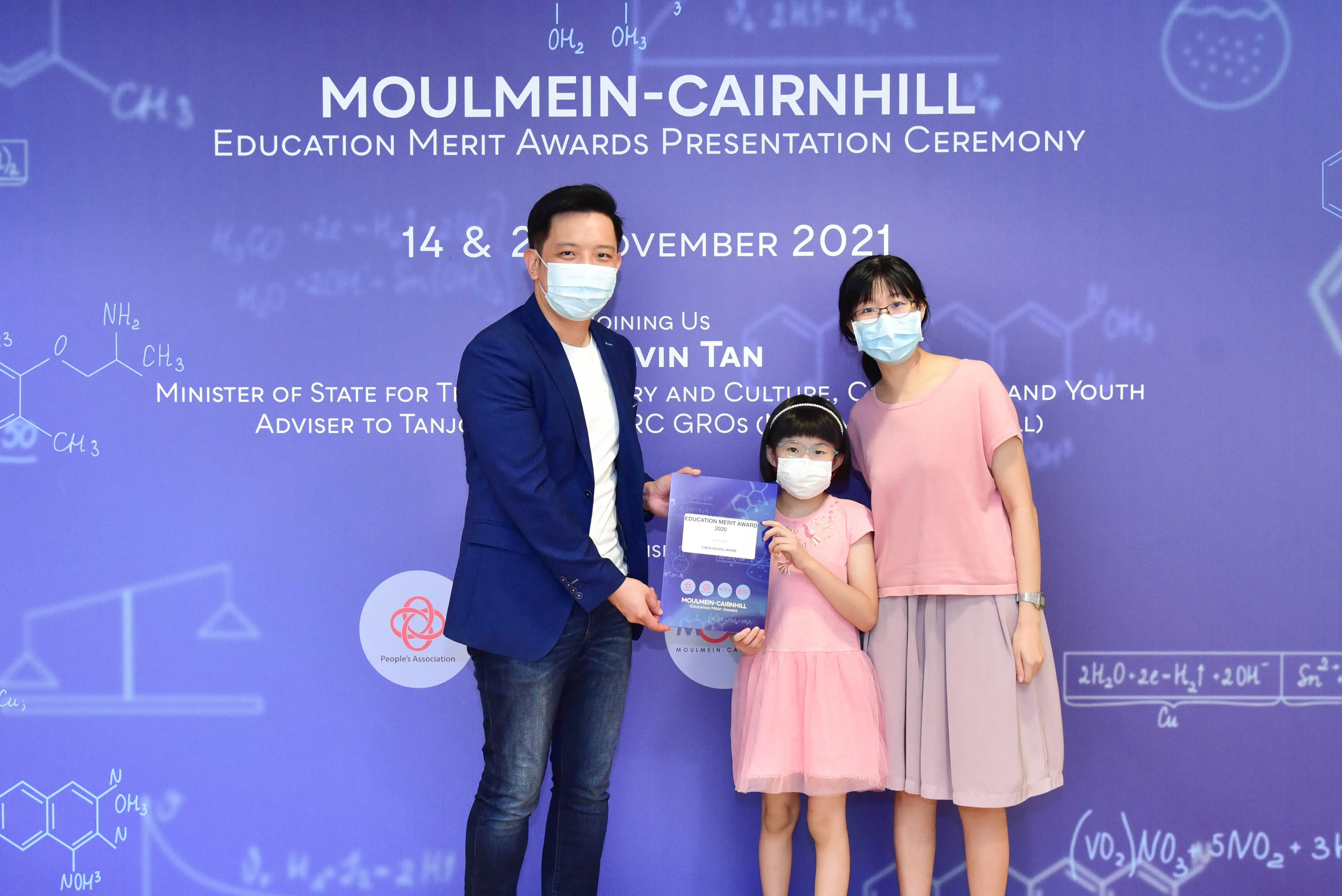 Three masked people pose with an award certificate at the Moulmein-Cairnhill Education Merit Awards Ceremony, November 2021.
