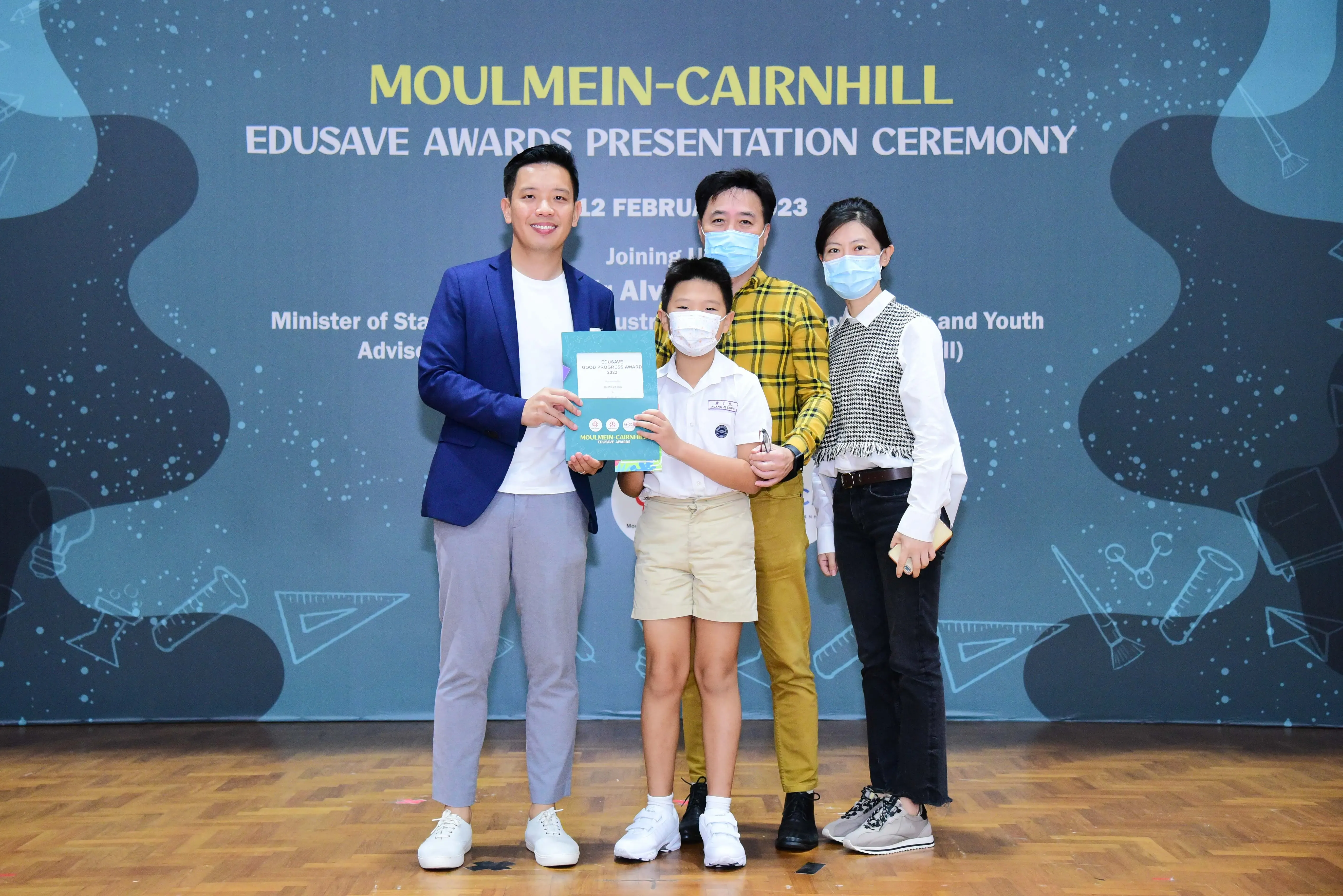 Four people pose with an award certificate at the Moulmein-Cairnhill Edusave Awards Presentation Ceremony.