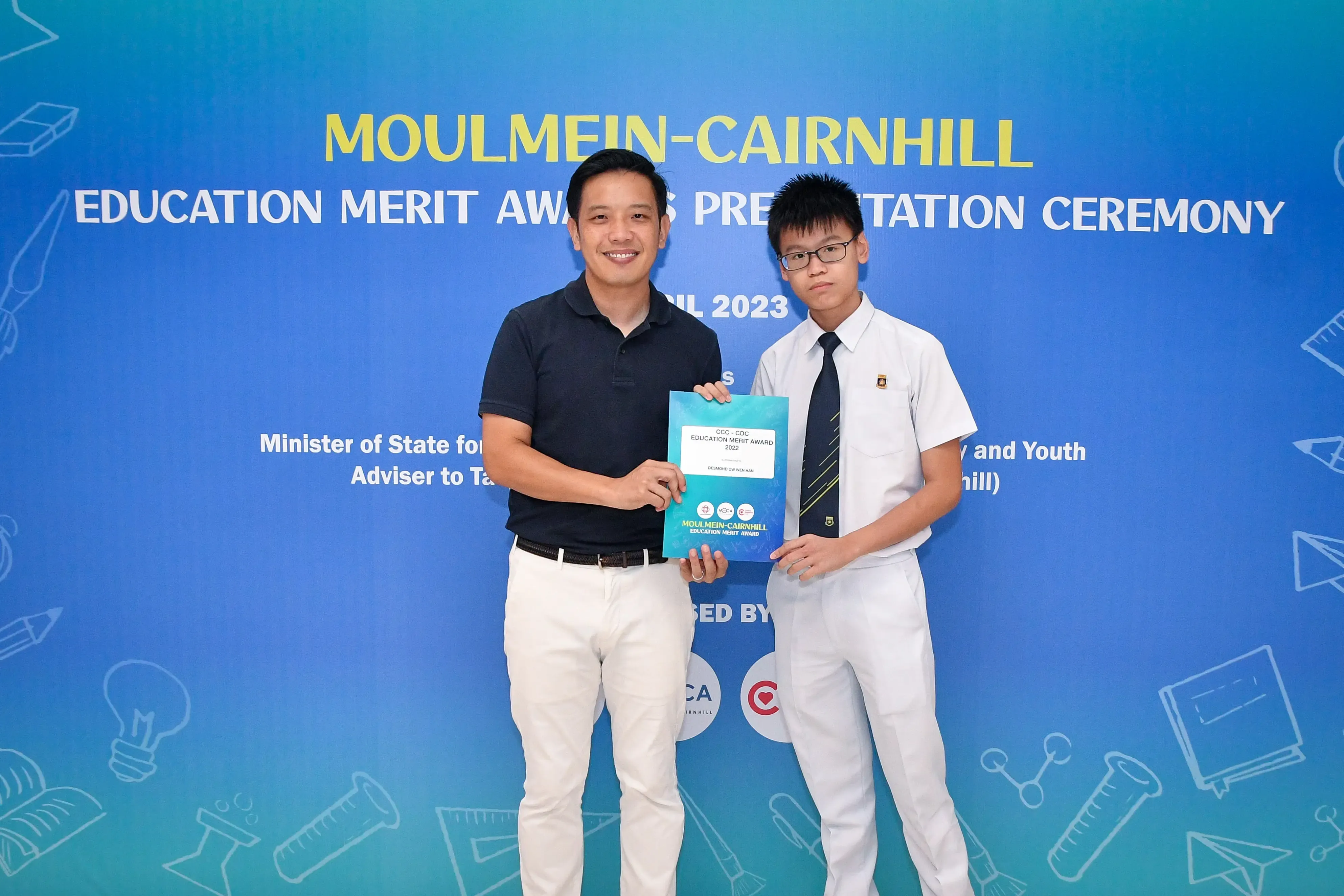 Two people hold an award certificate at the Moulmein-Cairnhill Education Merit Awards Presentation Ceremony 2023.