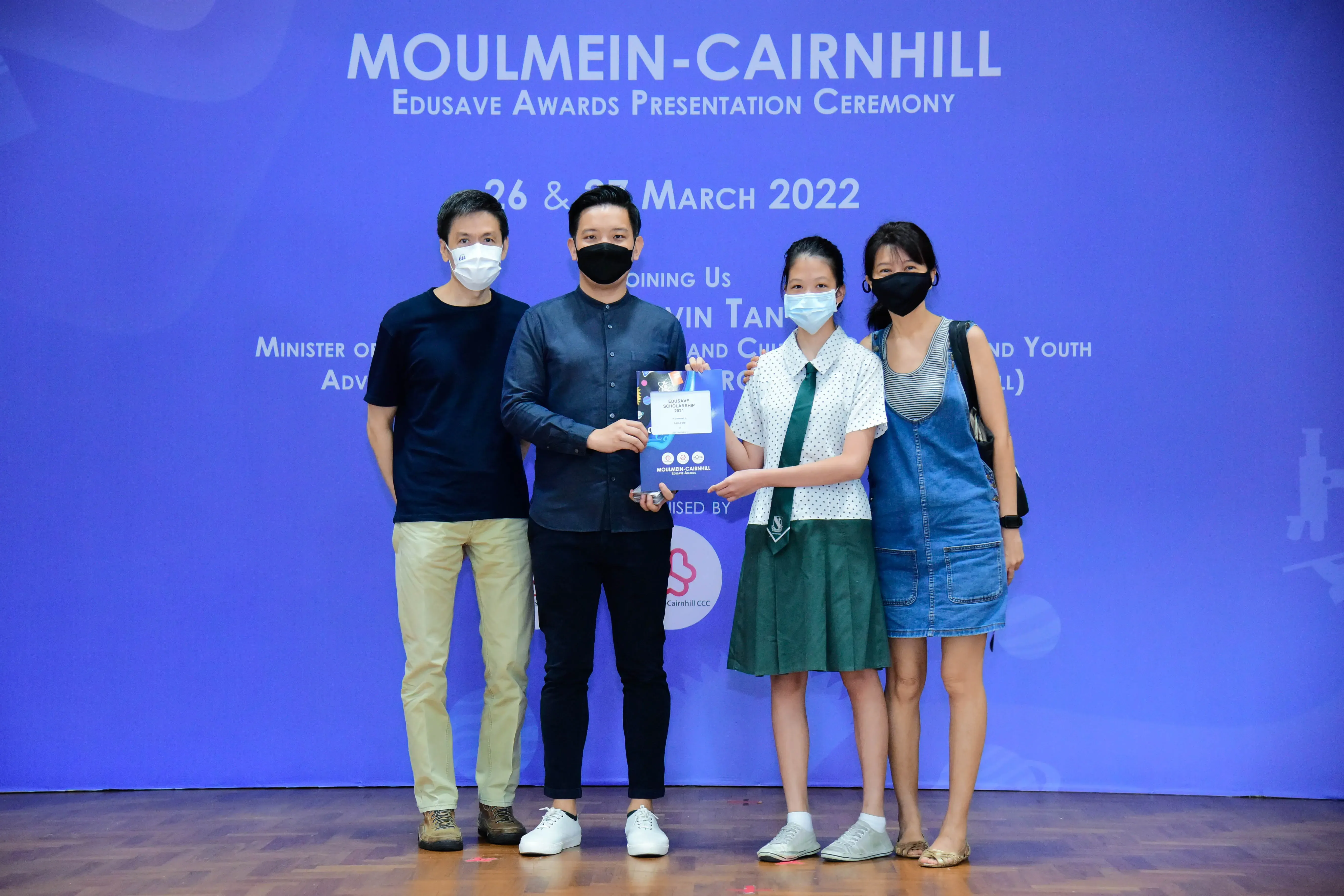 Four masked people pose at the Moulmein-Cairnhill Edusave Awards Presentation Ceremony on March 26-27, 2022.