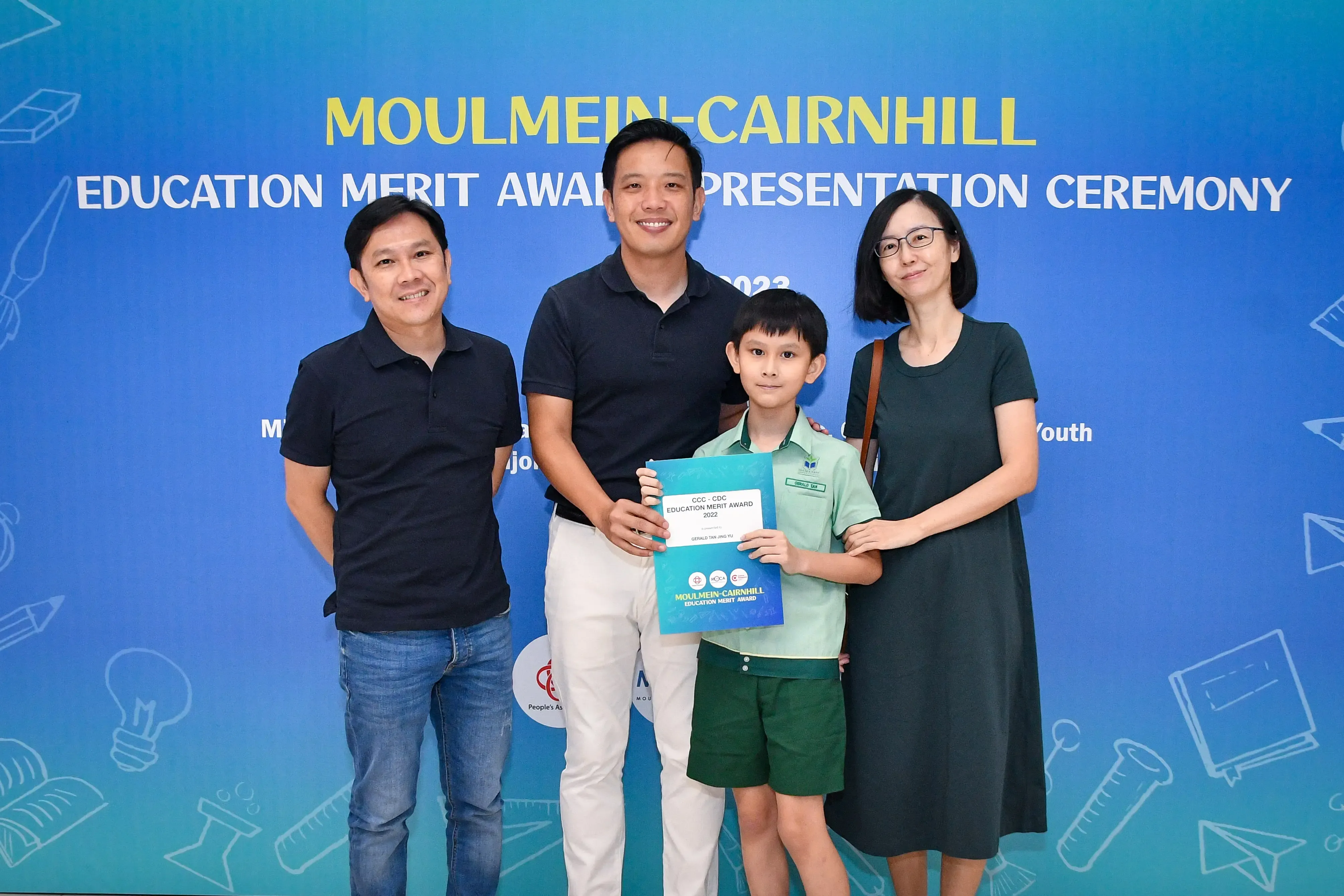 Three adults and a young boy holding a certificate at the Moulmein-Cairnhill Education Merit Award Presentation Ceremony.