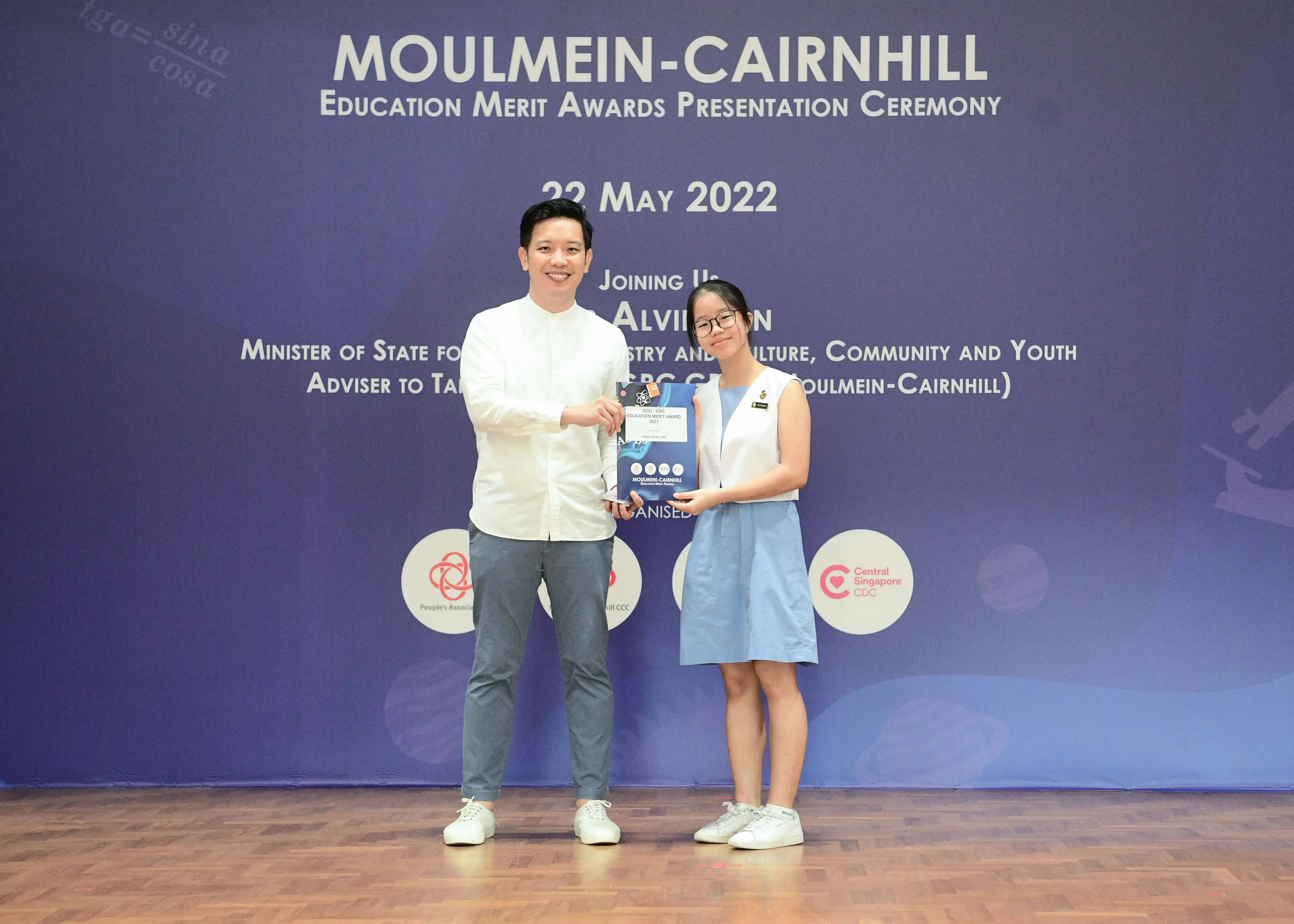Two people holding an award at the Moulmein-Cairnhill Education Merit Awards Ceremony on 22 May 2022.