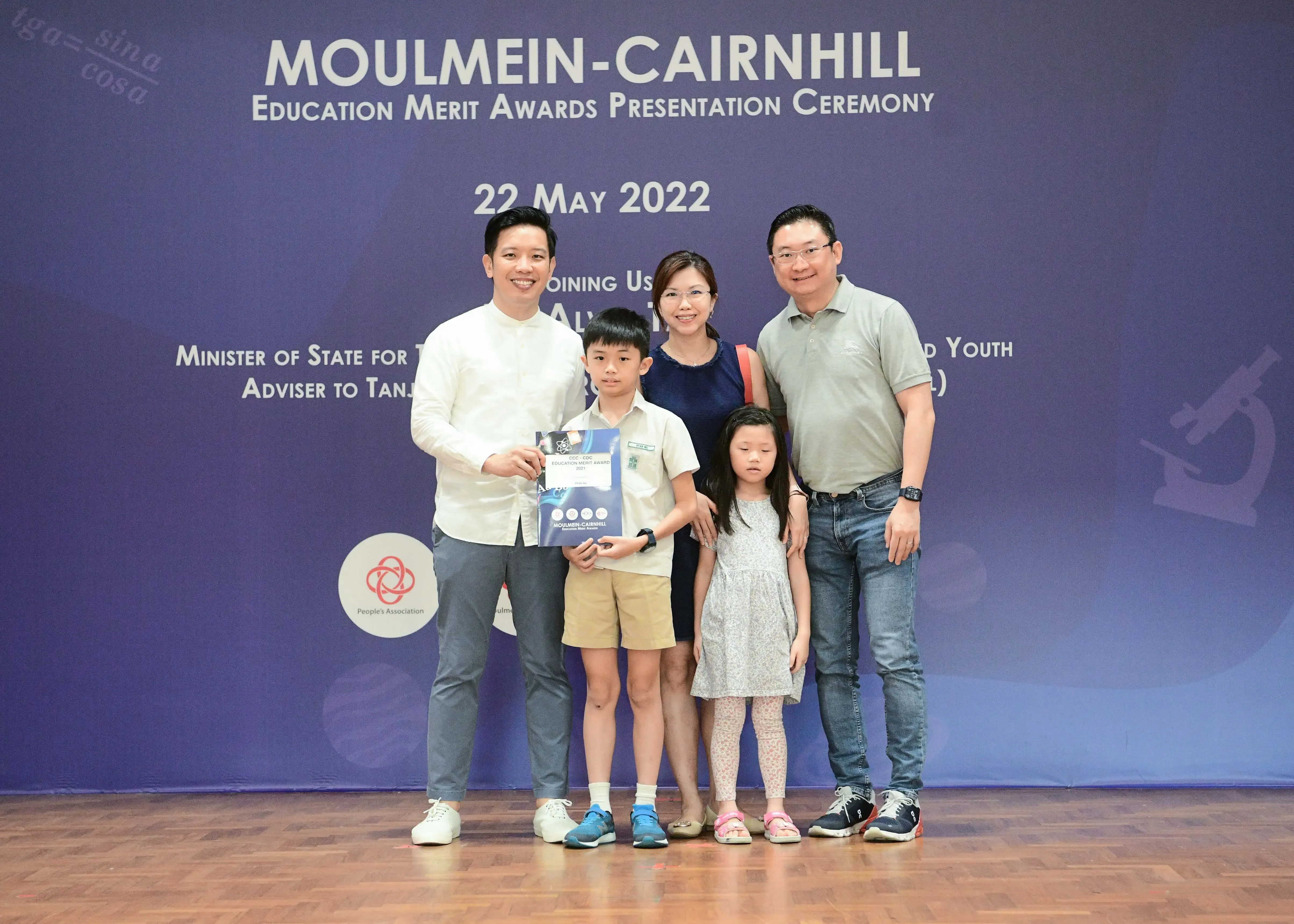 Family of four posing with an official at the Moulmein-Cairnhill Education Merit Awards ceremony on 22 May 2022.