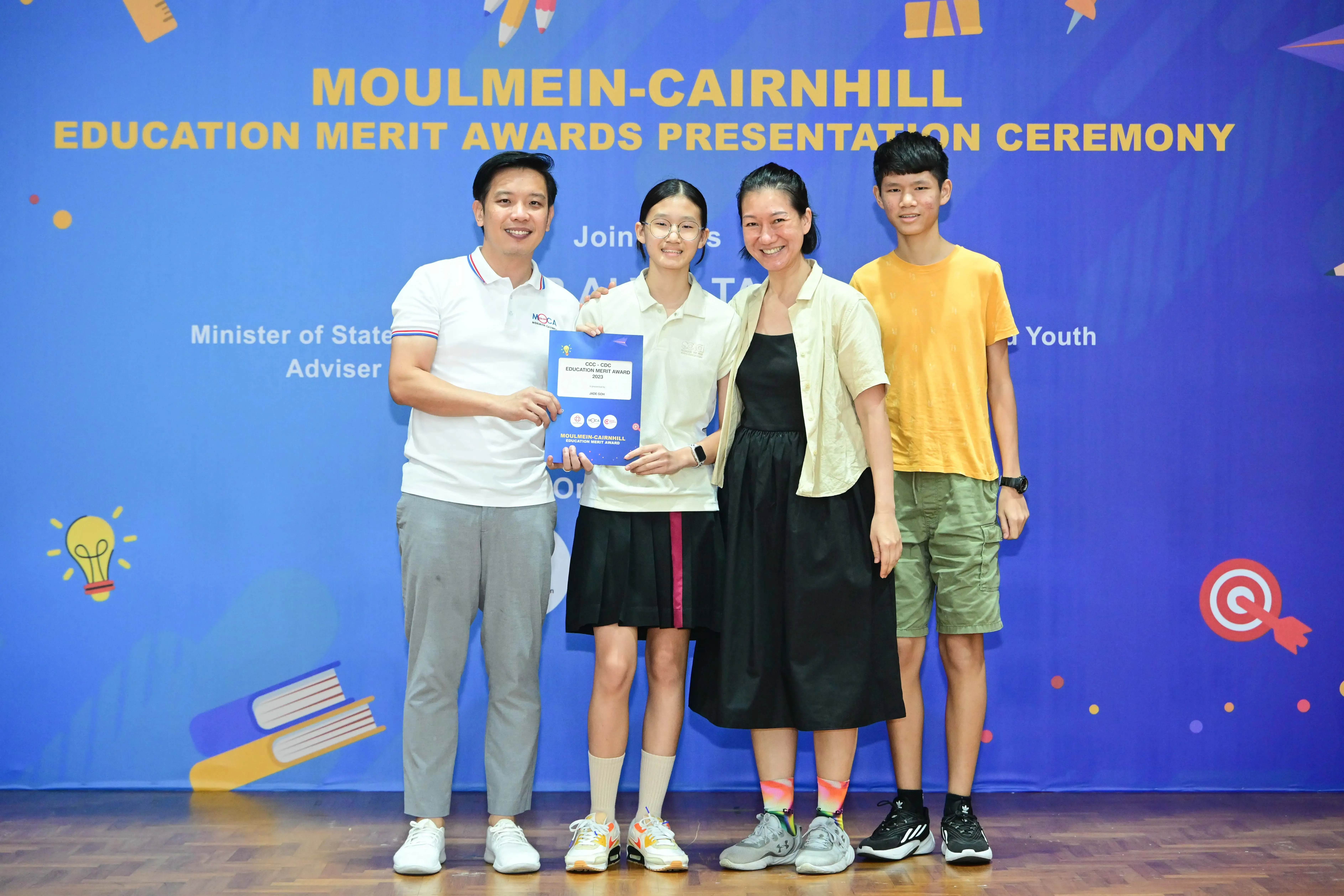 Four people posing with an award certificate at the Moulmein-Cairnhill Education Merit Awards Presentation Ceremony.