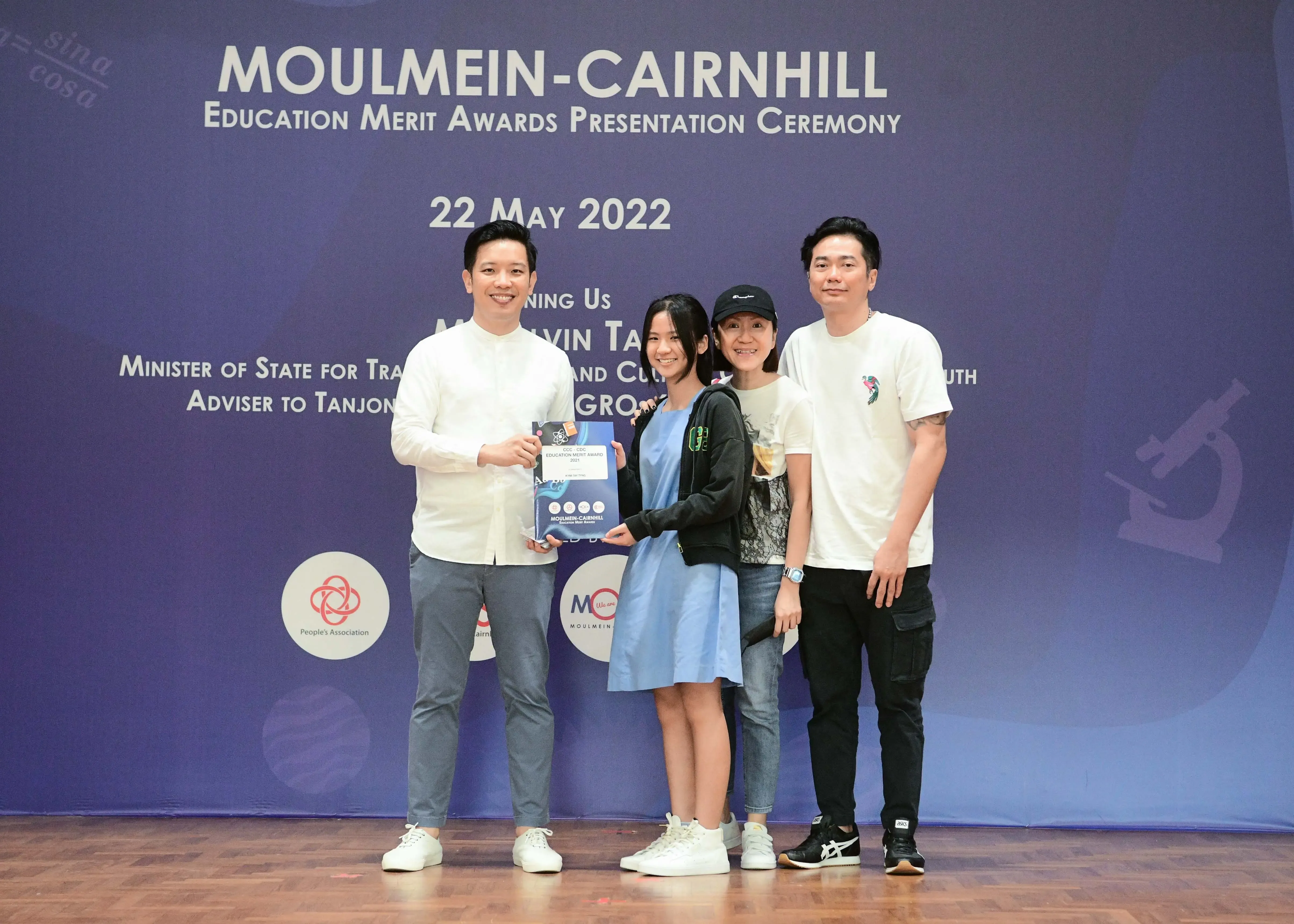 Four people pose on a stage at the Moulmein-Cairnhill Education Merit Awards Presentation Ceremony on 22 May 2022.