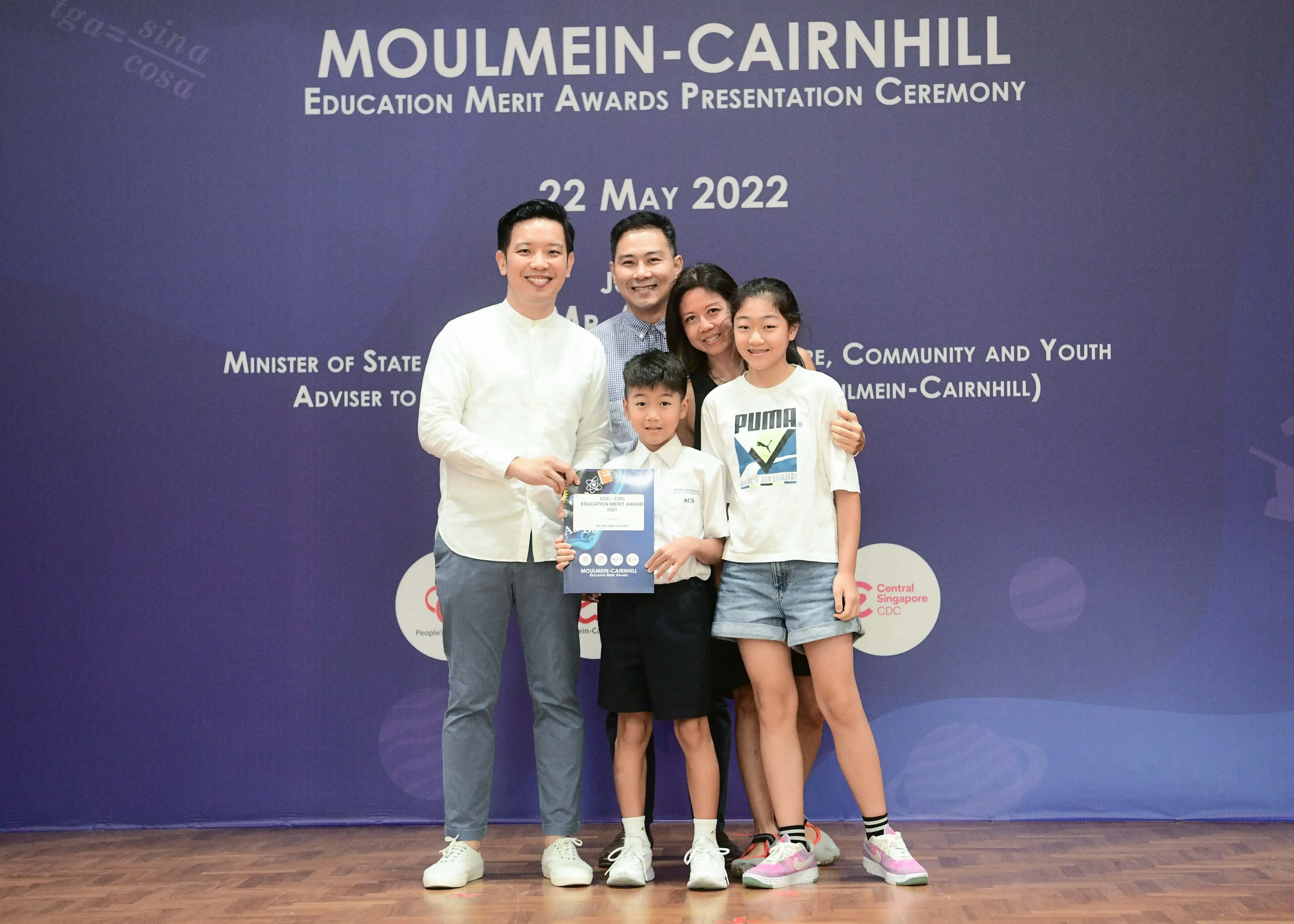 Five people pose with an award certificate at the Moulmein-Cairnhill Education Merit Awards Ceremony on 22 May 2022.
