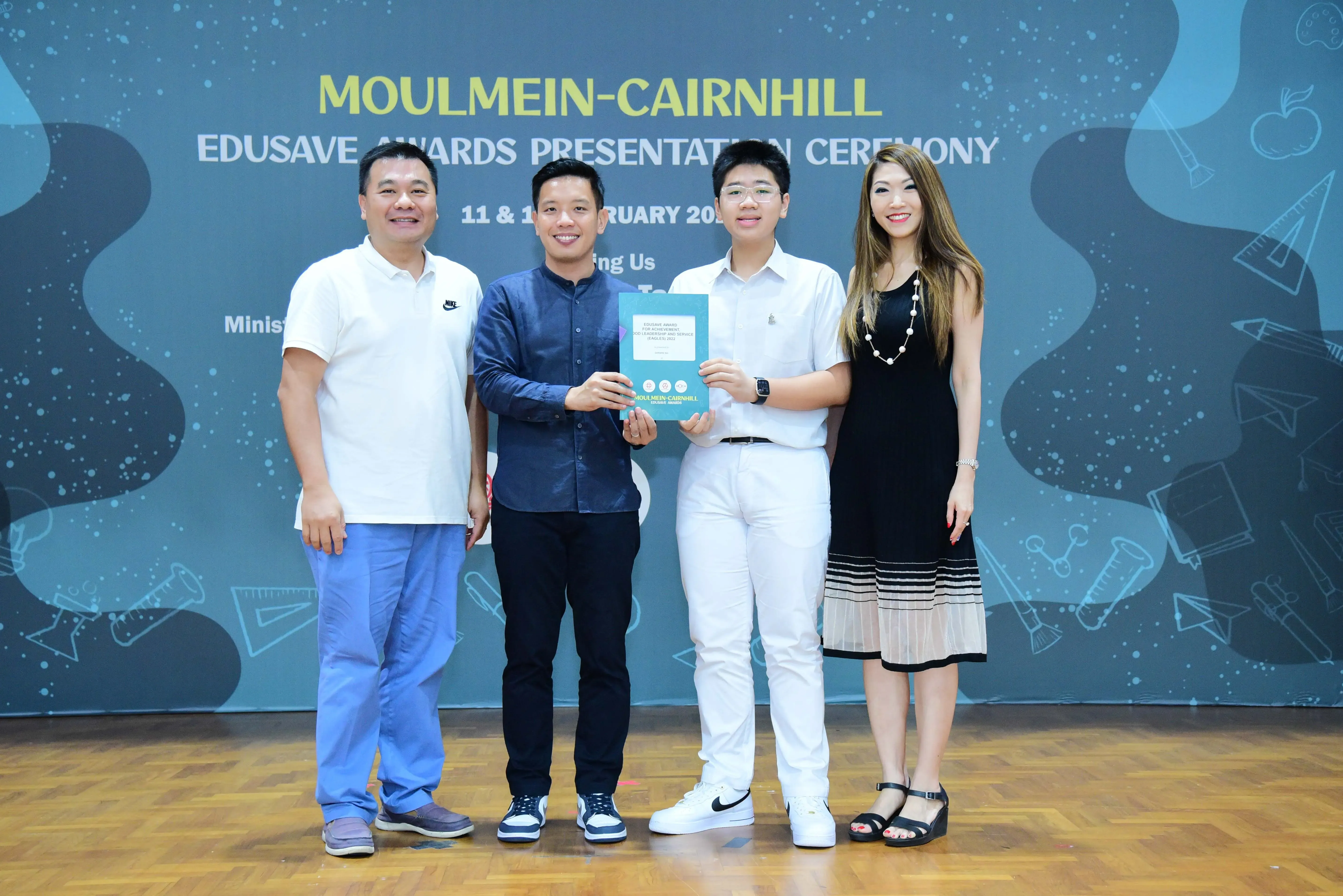 Four people pose at the Moulmein-Cairnhill Edusave Awards Presentation Ceremony, with two holding a certificate.