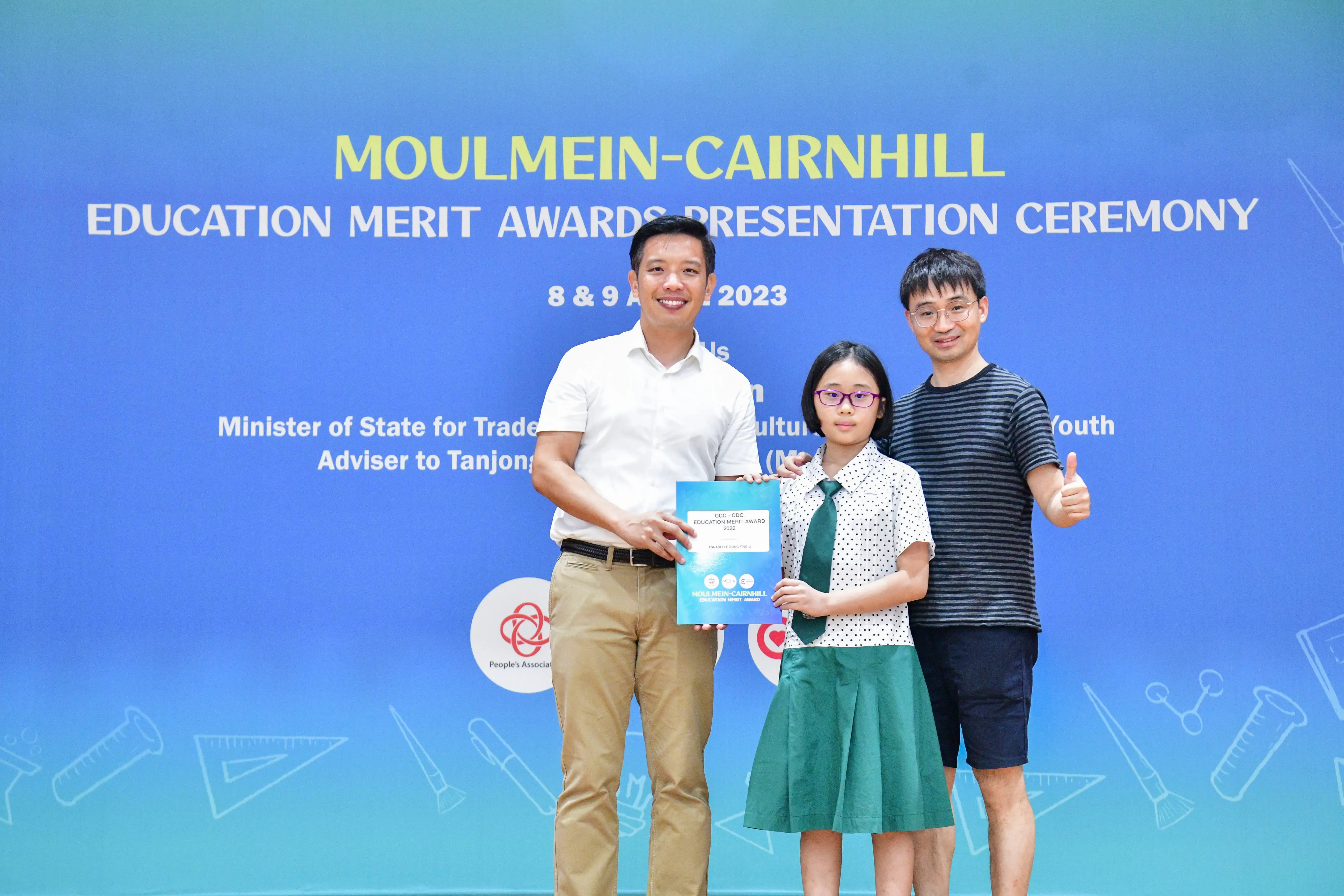 Two men and a girl in school uniform hold an award certificate at the Moulmein-Cairnhill Education Merit Awards 2023.