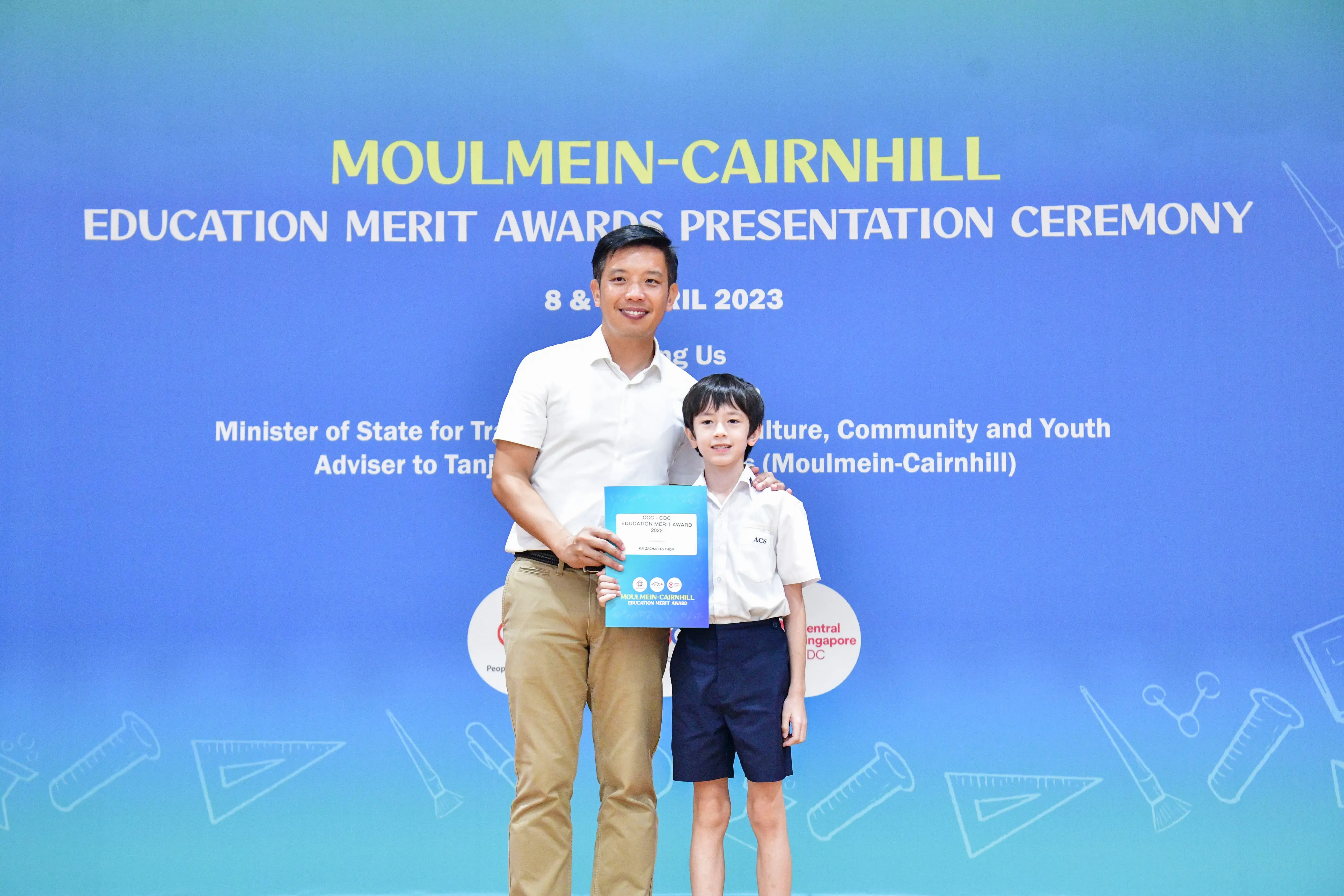 A man and a young boy pose together holding an award certificate at the Moulmein-Cairnhill Education Merit Awards 2023.