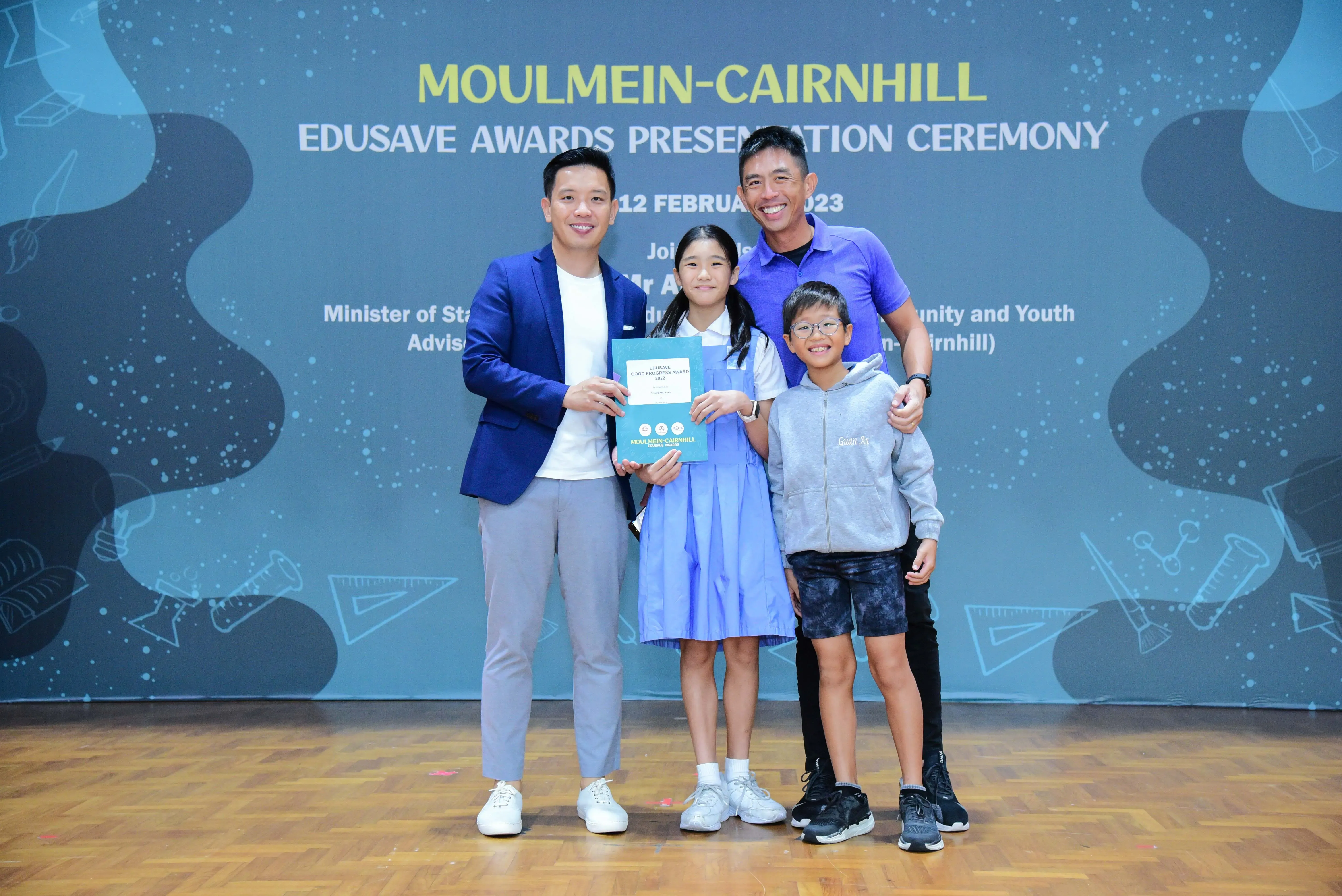 Two adults and two children pose smiling at the Moulmein-Cairnhill Edusave Awards Presentation Ceremony on 12 February 2023.