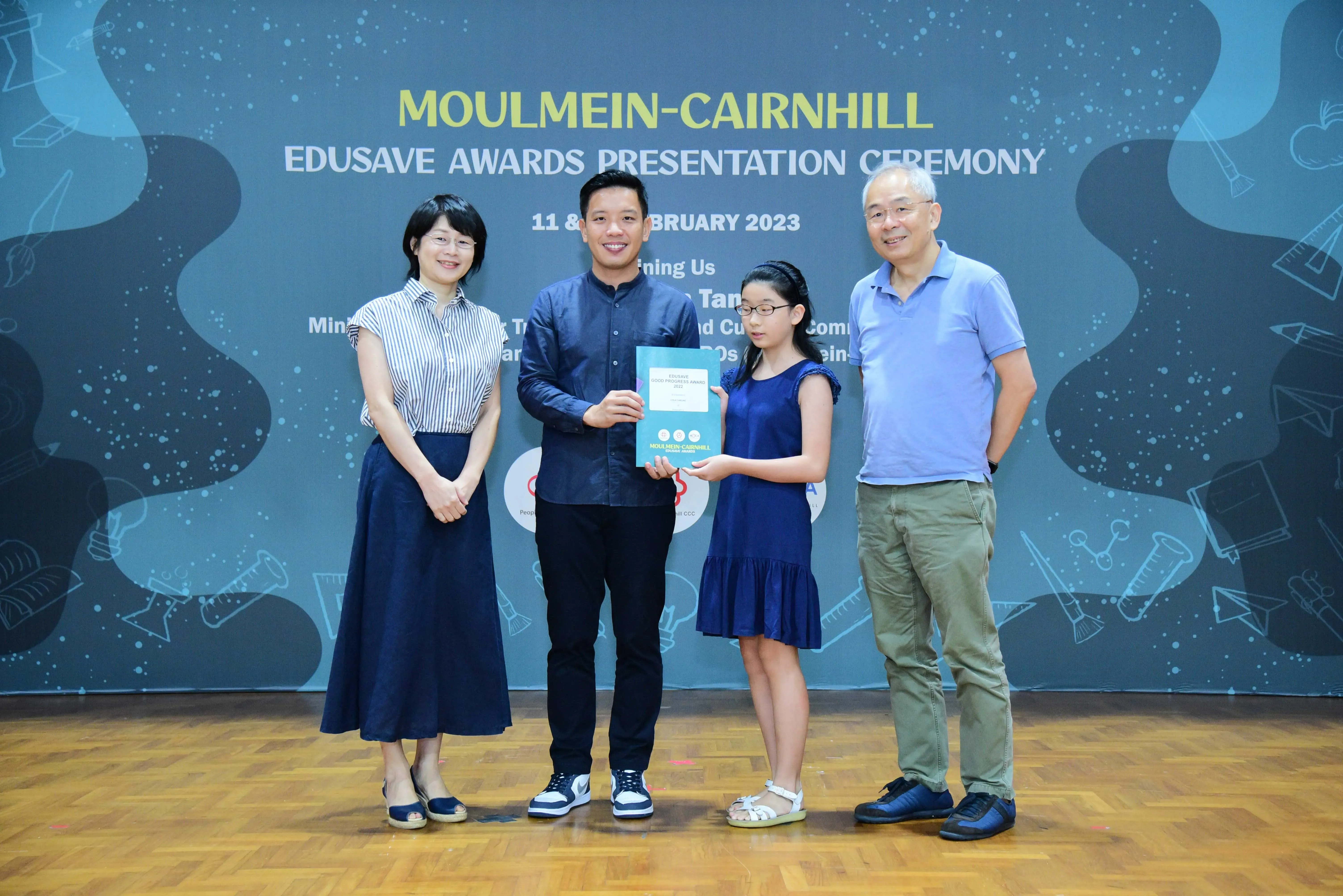 Four people pose holding a certificate at the Moulmein-Cairnhill Edusave Awards Presentation Ceremony, February 2023.