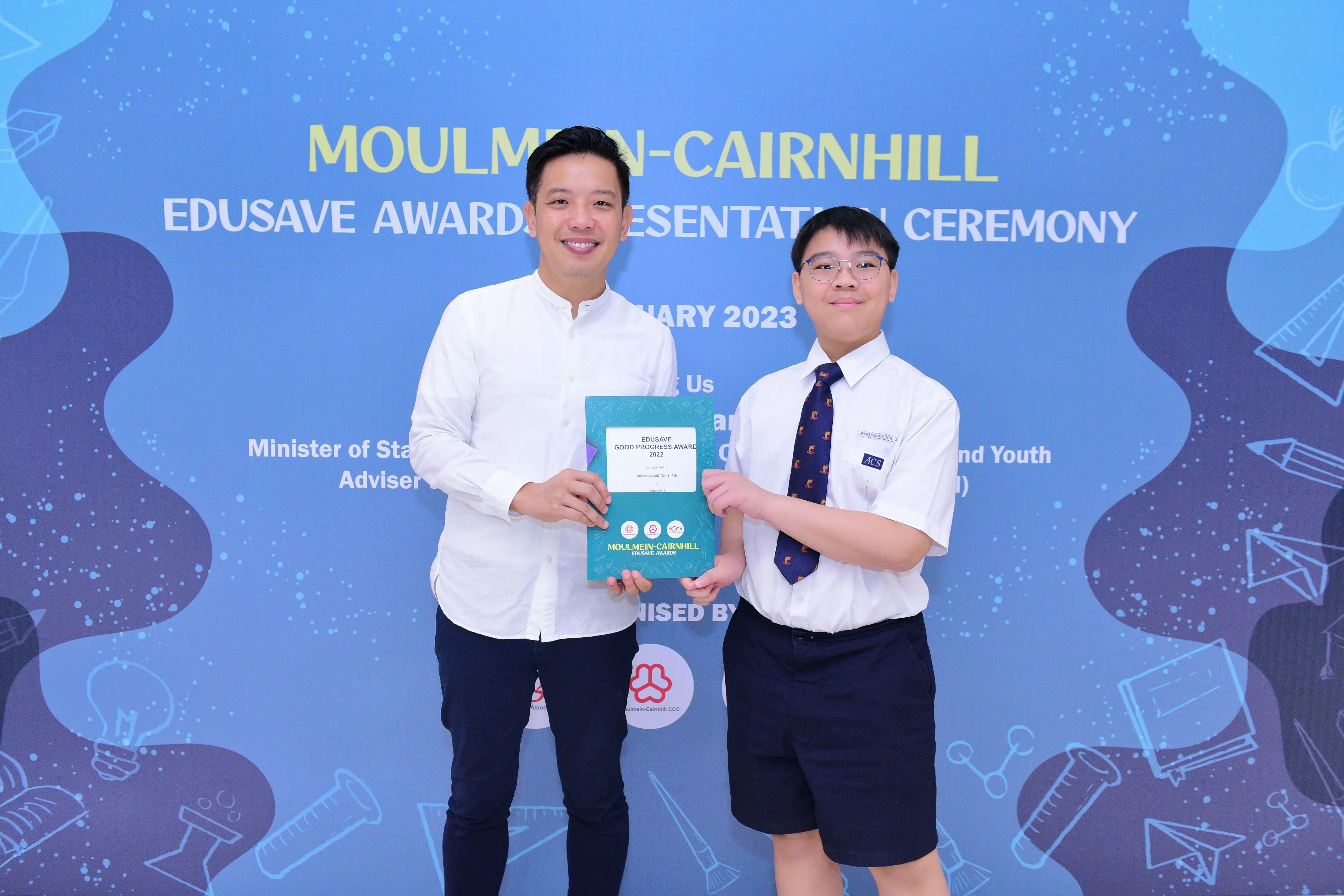 A man and a uniformed student hold an Edusave Good Progress Award at the Moulmein-Cairnhill ceremony in 2023.