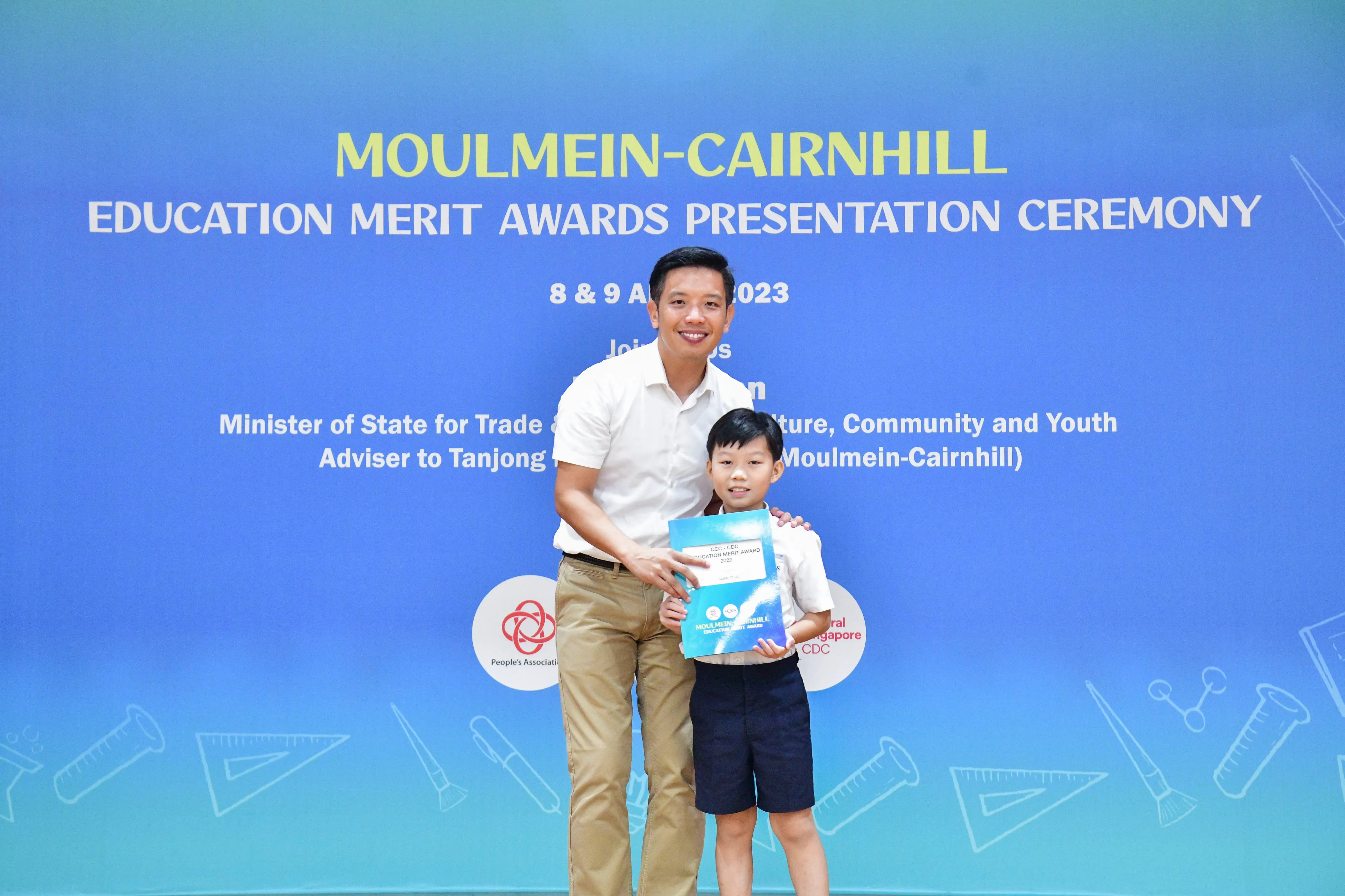 A man and young boy pose together holding an award at the Moulmein-Cairnhill Education Merit Awards Ceremony 2023.
