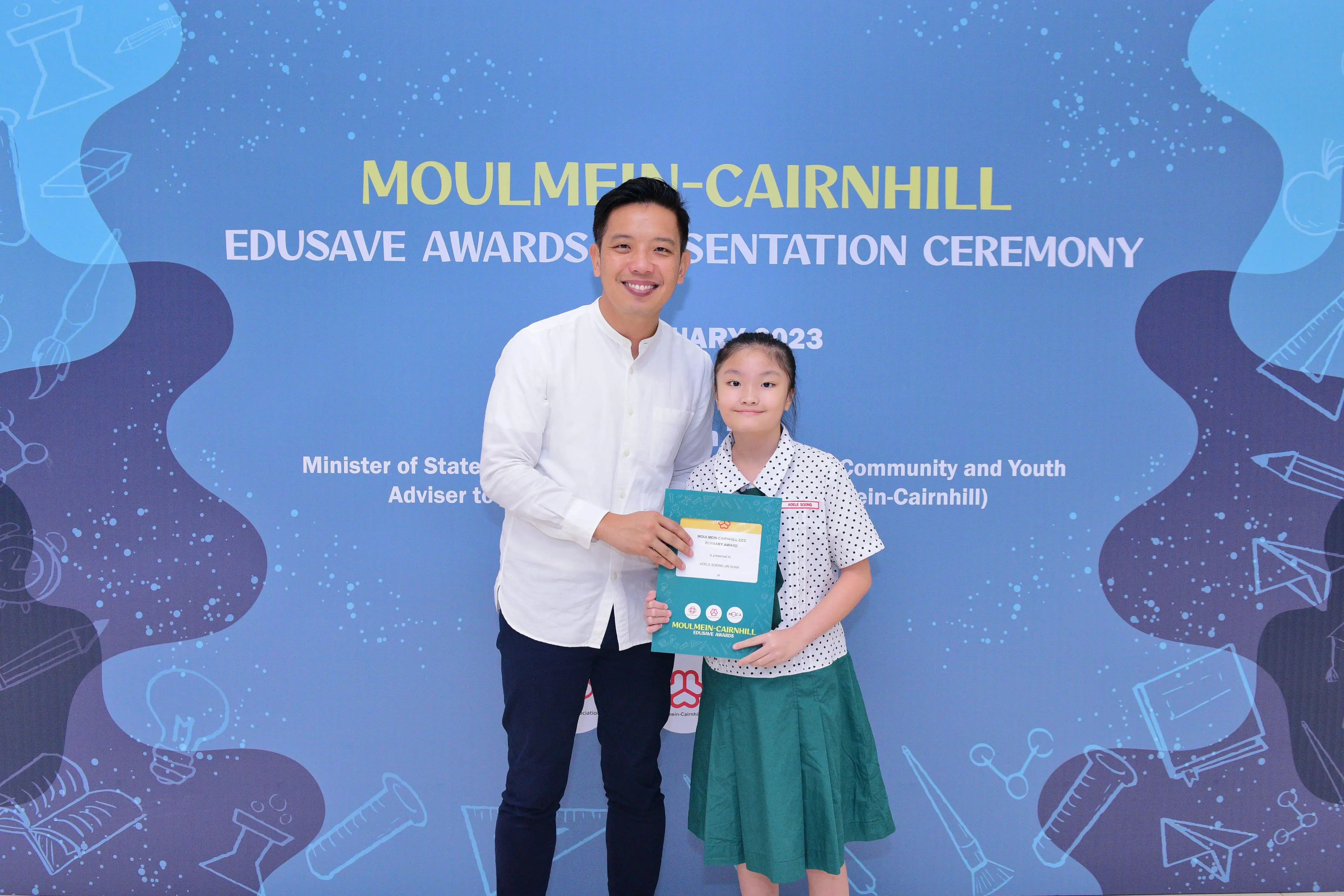 A man and a young girl hold a certificate at the Moulmein-Cairnhill Edusave Awards Presentation Ceremony 2023.