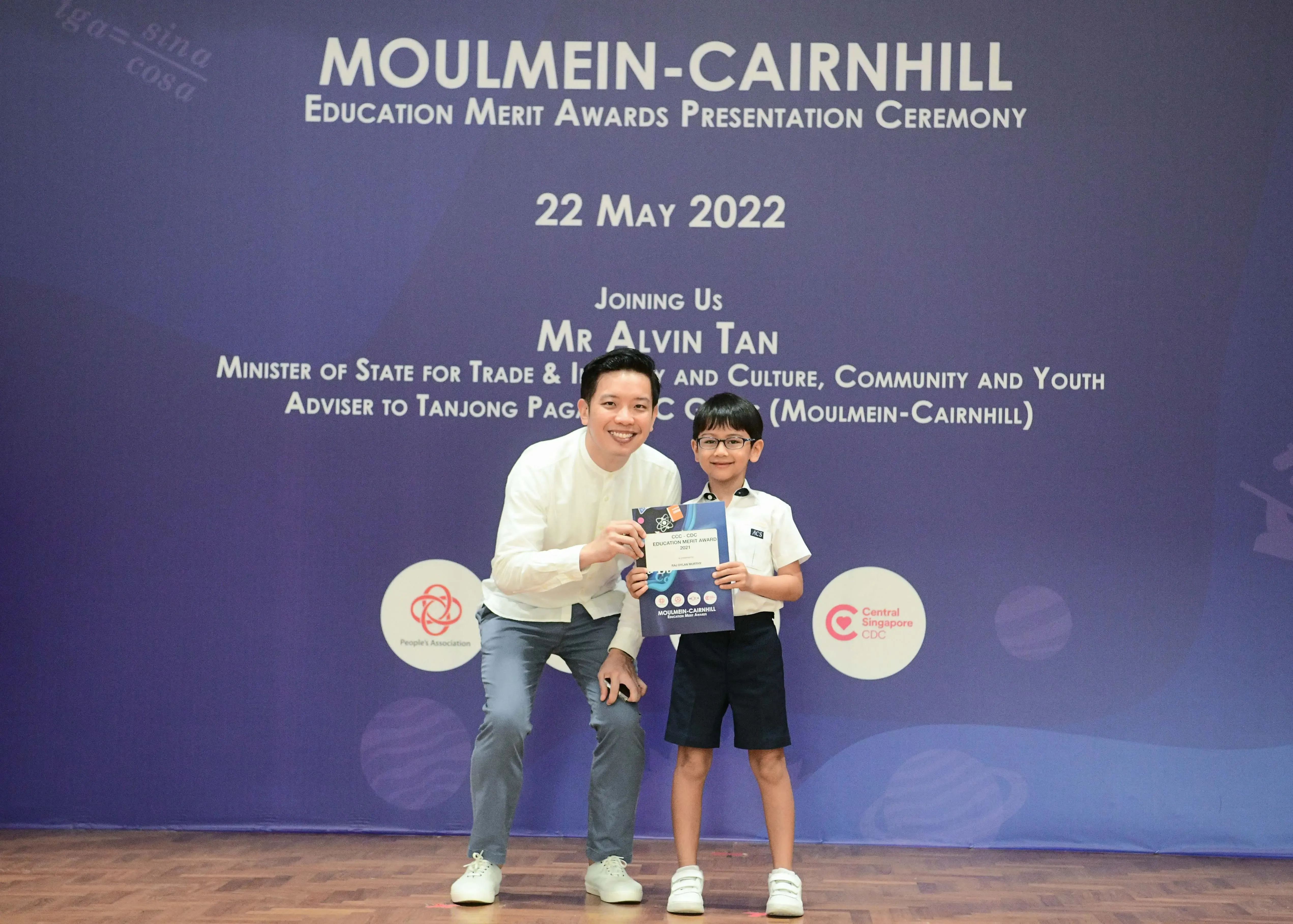 A man and a young boy hold an award certificate at the Moulmein-Cairnhill Education Merit Awards on 22 May 2022.