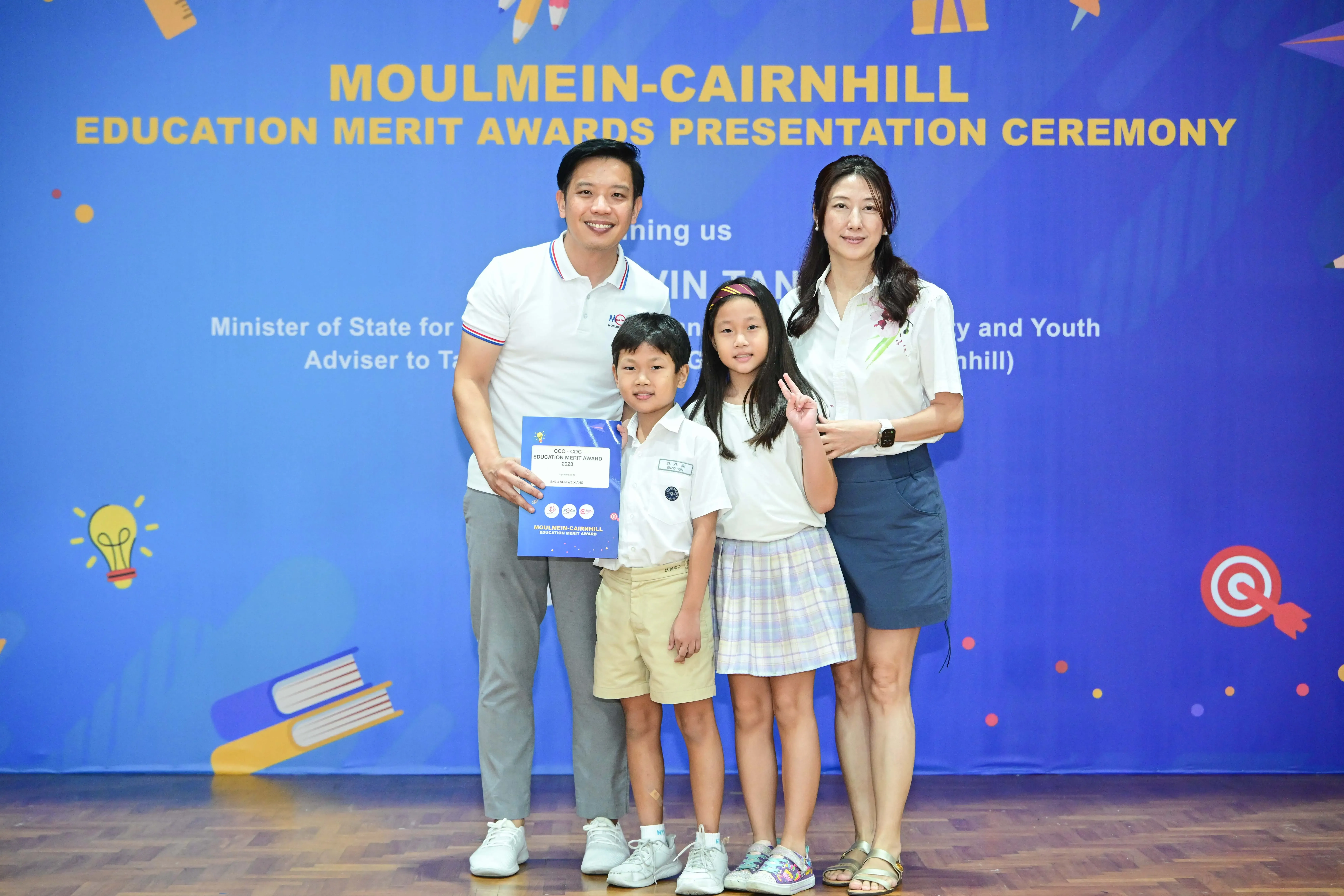 Family of four posing at Moulmein-Cairnhill Education Merit Awards Presentation Ceremony, boy holding a certificate.