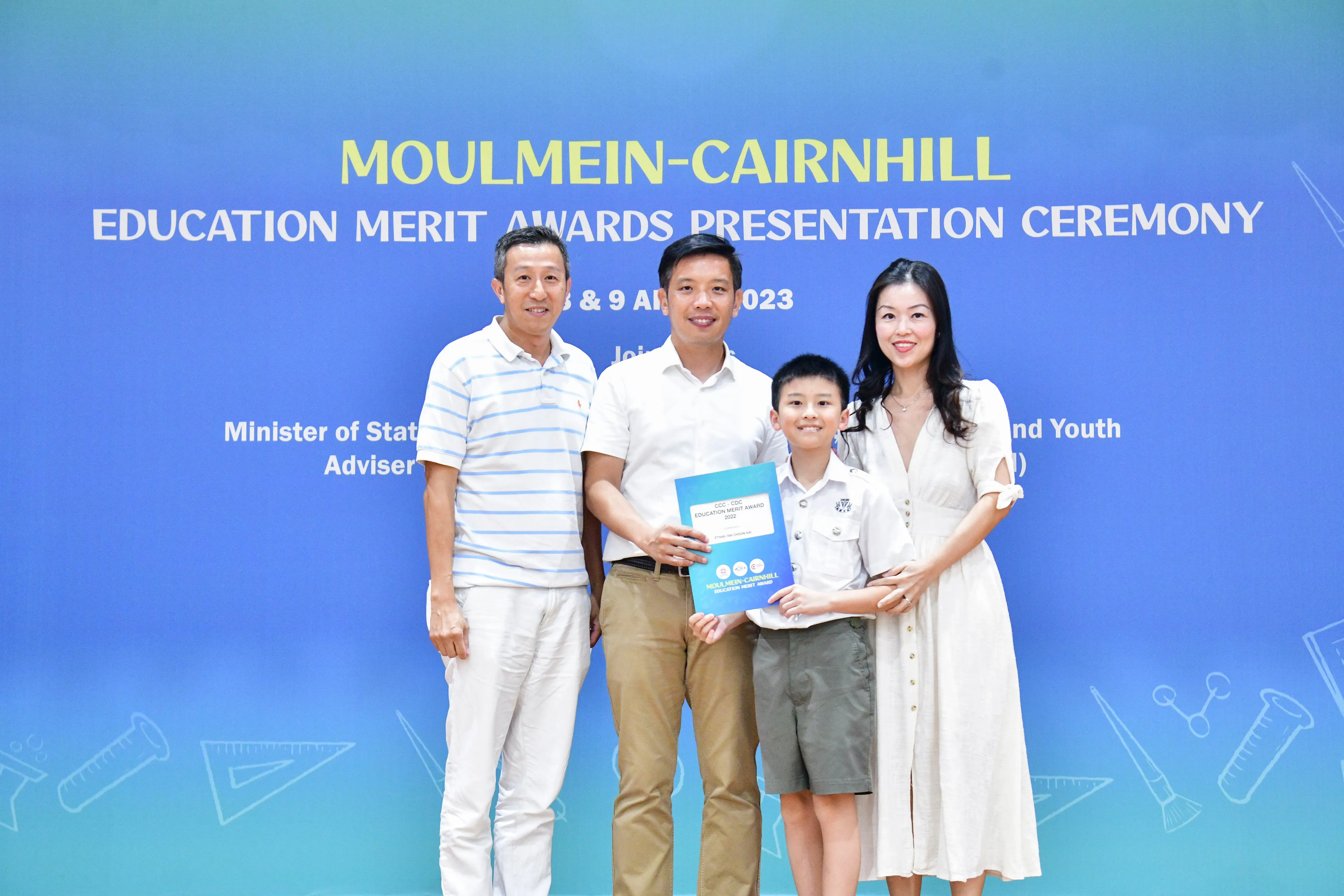 Three adults and a boy holding an award certificate at the Moulmein-Cairnhill Education Merit Awards Ceremony 2023.