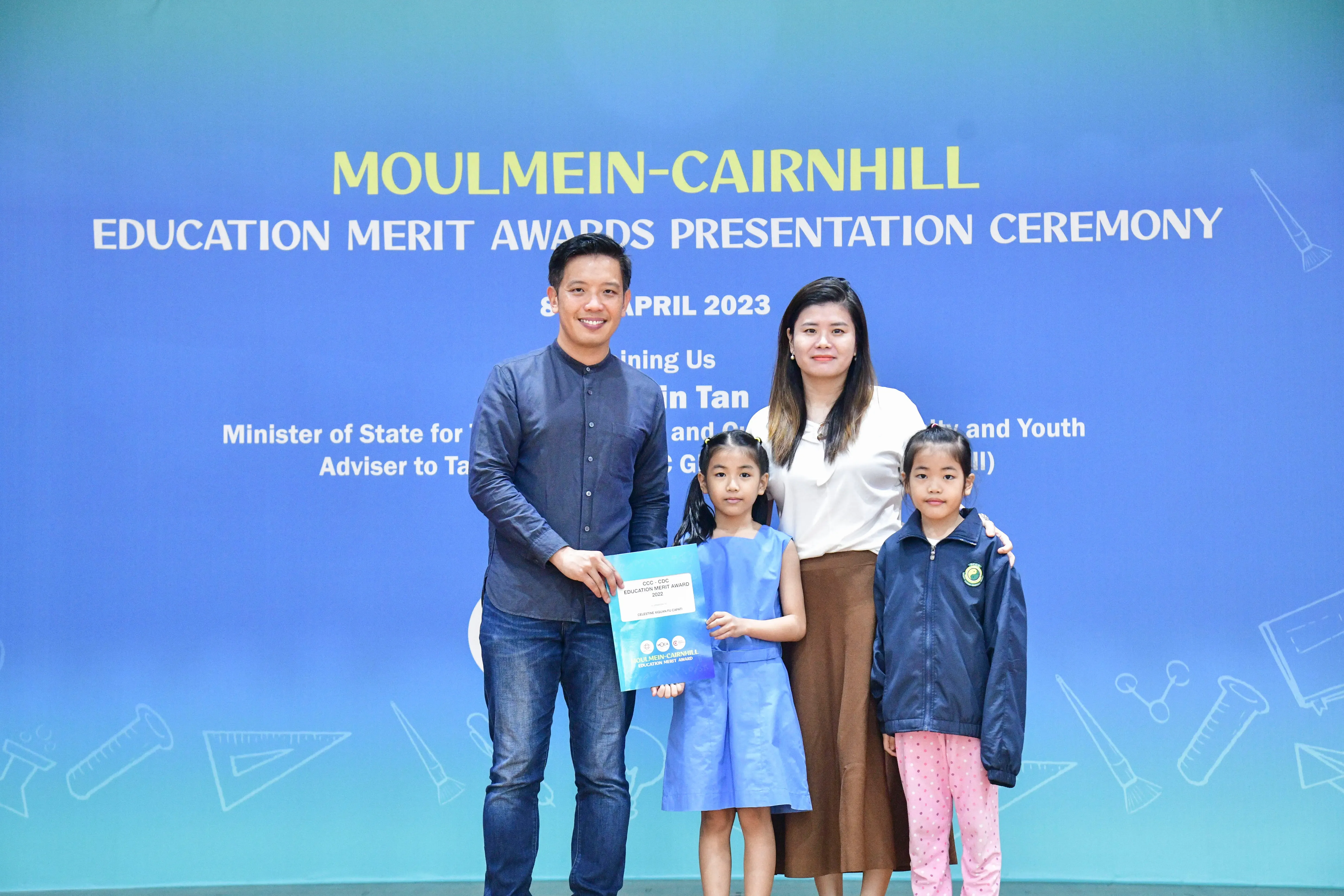 Two adults and two children pose with an award certificate at the Moulmein-Cairnhill Education Merit Awards 2023.
