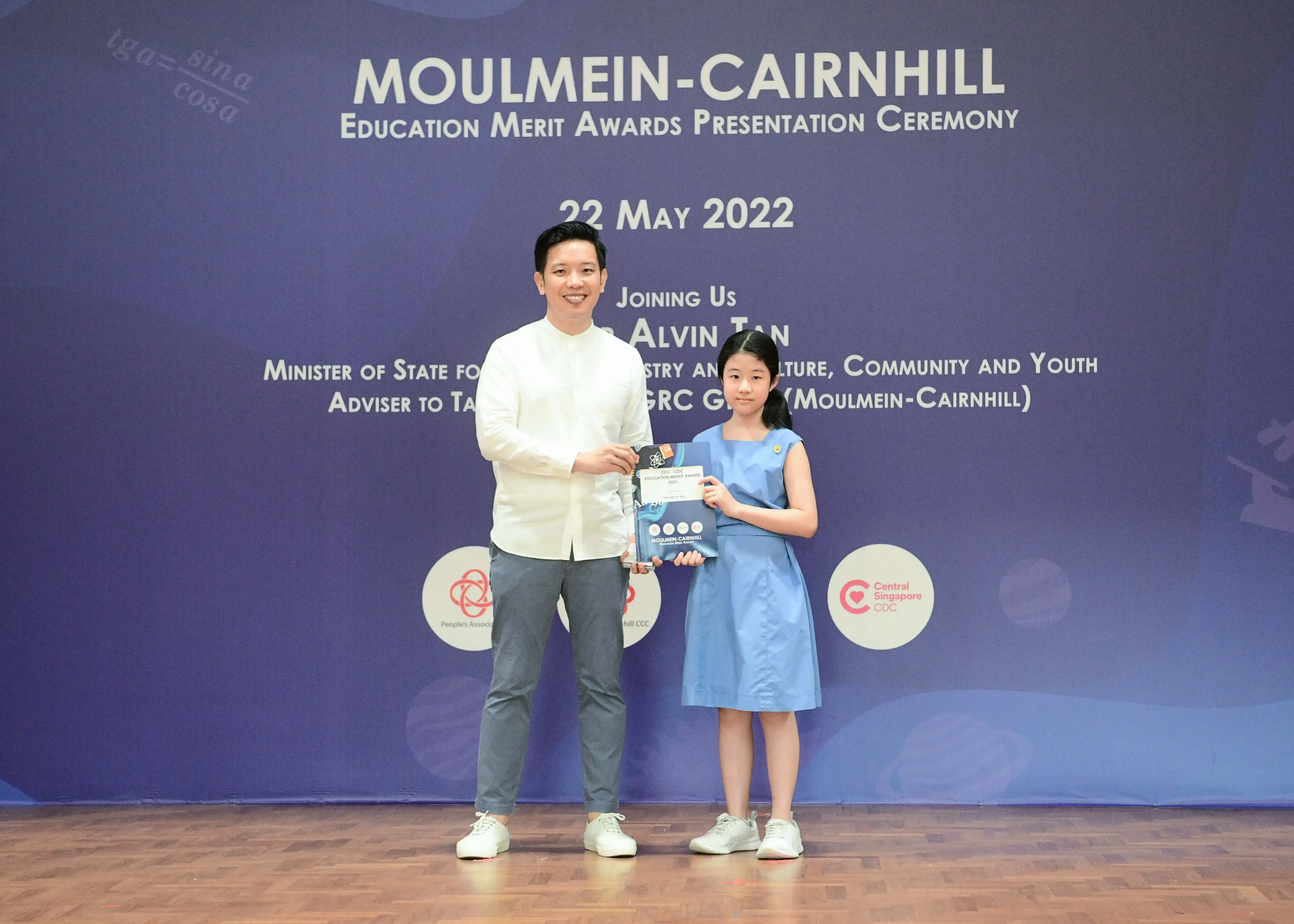 A man and a young girl hold an award together at the Moulmein-Cairnhill Education Merit Awards Ceremony on 22 May 2022.