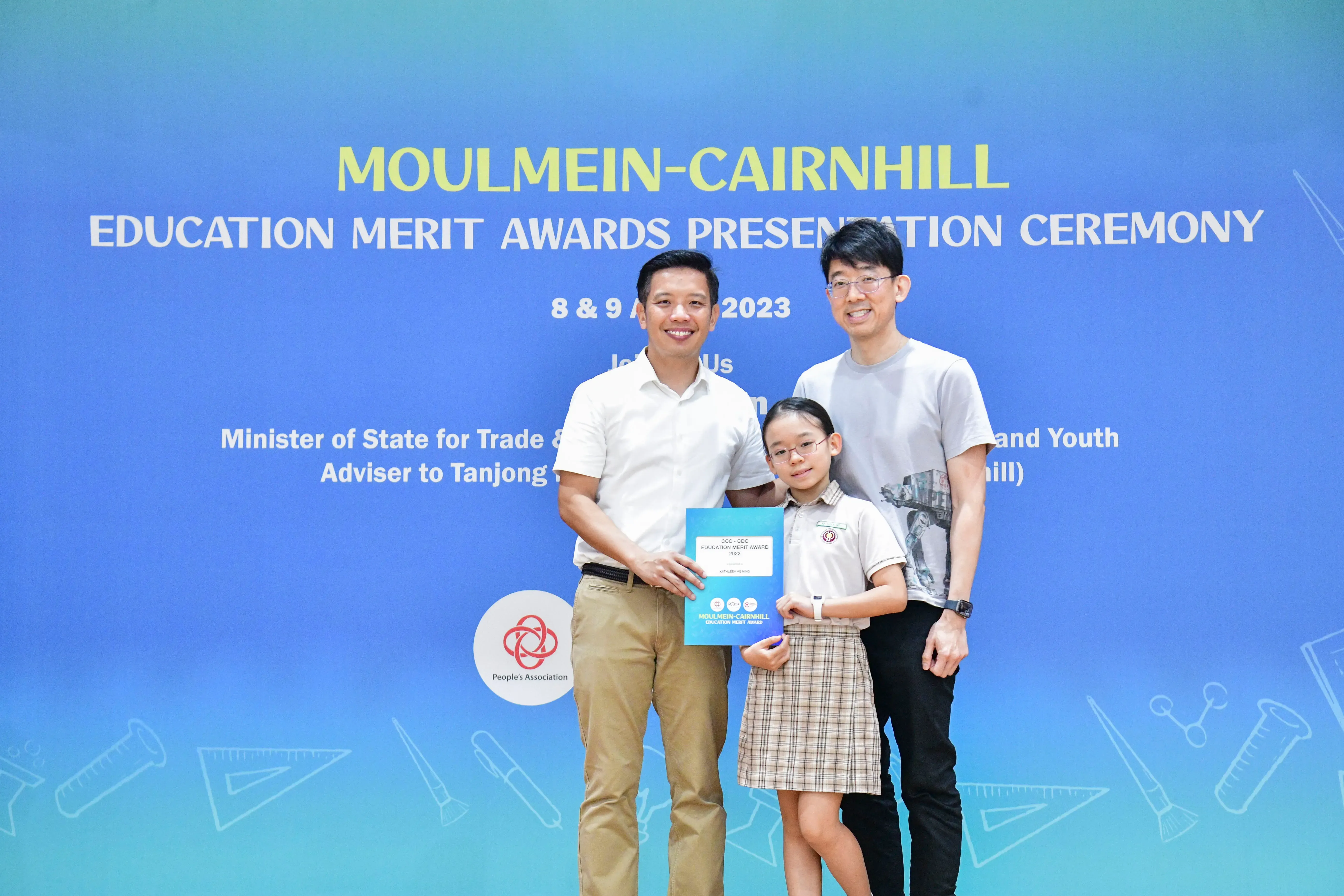 Two men and a young girl holding a certificate pose at the Moulmein-Cairnhill Education Merit Awards 2023.