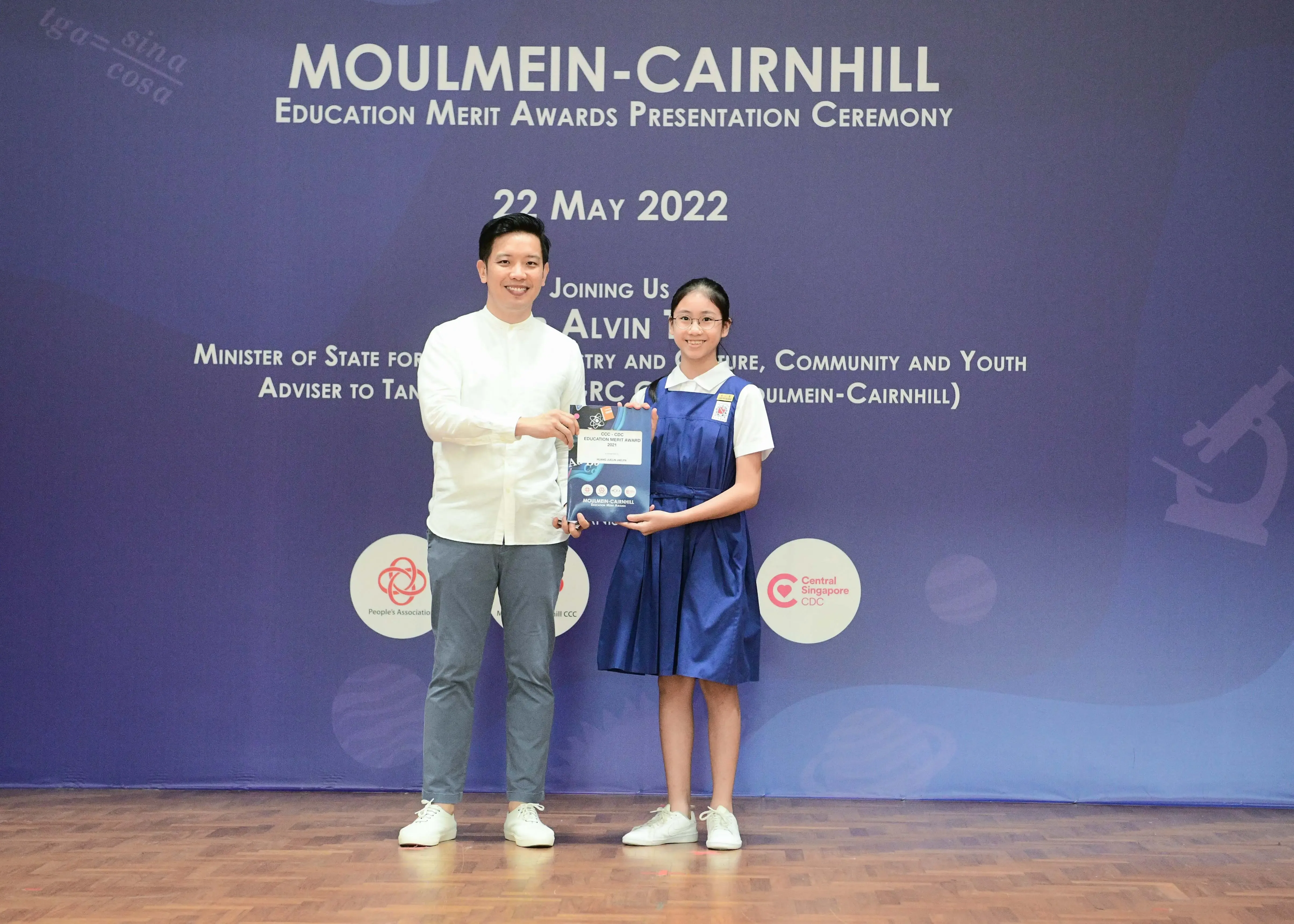 A man and a young girl hold an award together at the Moulmein-Cairnhill Education Merit Awards ceremony on 22 May 2022.