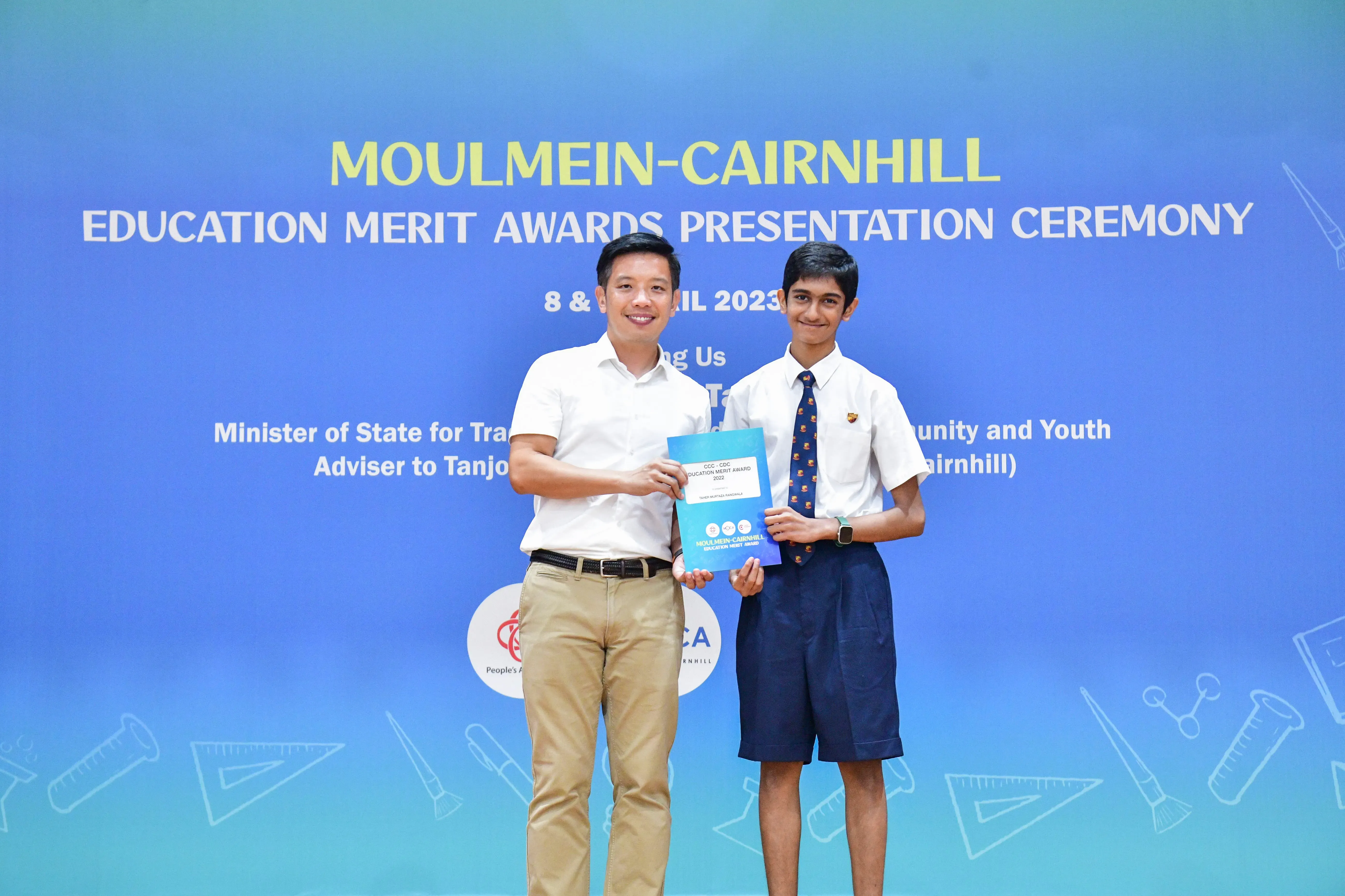 Two people hold an award certificate at the Moulmein-Cairnhill Education Merit Awards Presentation Ceremony 2023.