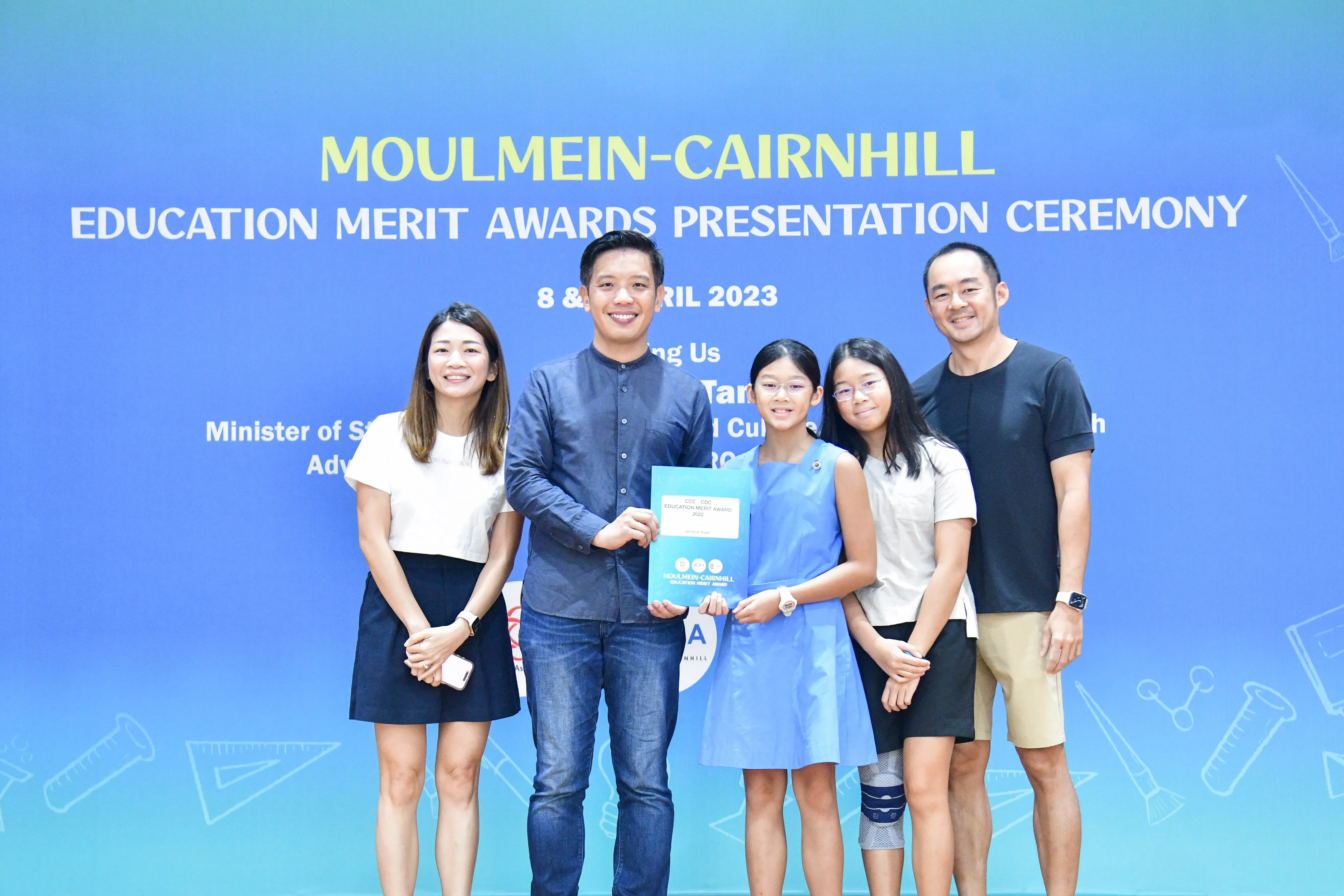 Five people pose with an award certificate at the Moulmein-Cairnhill Education Merit Awards Ceremony, April 2023.