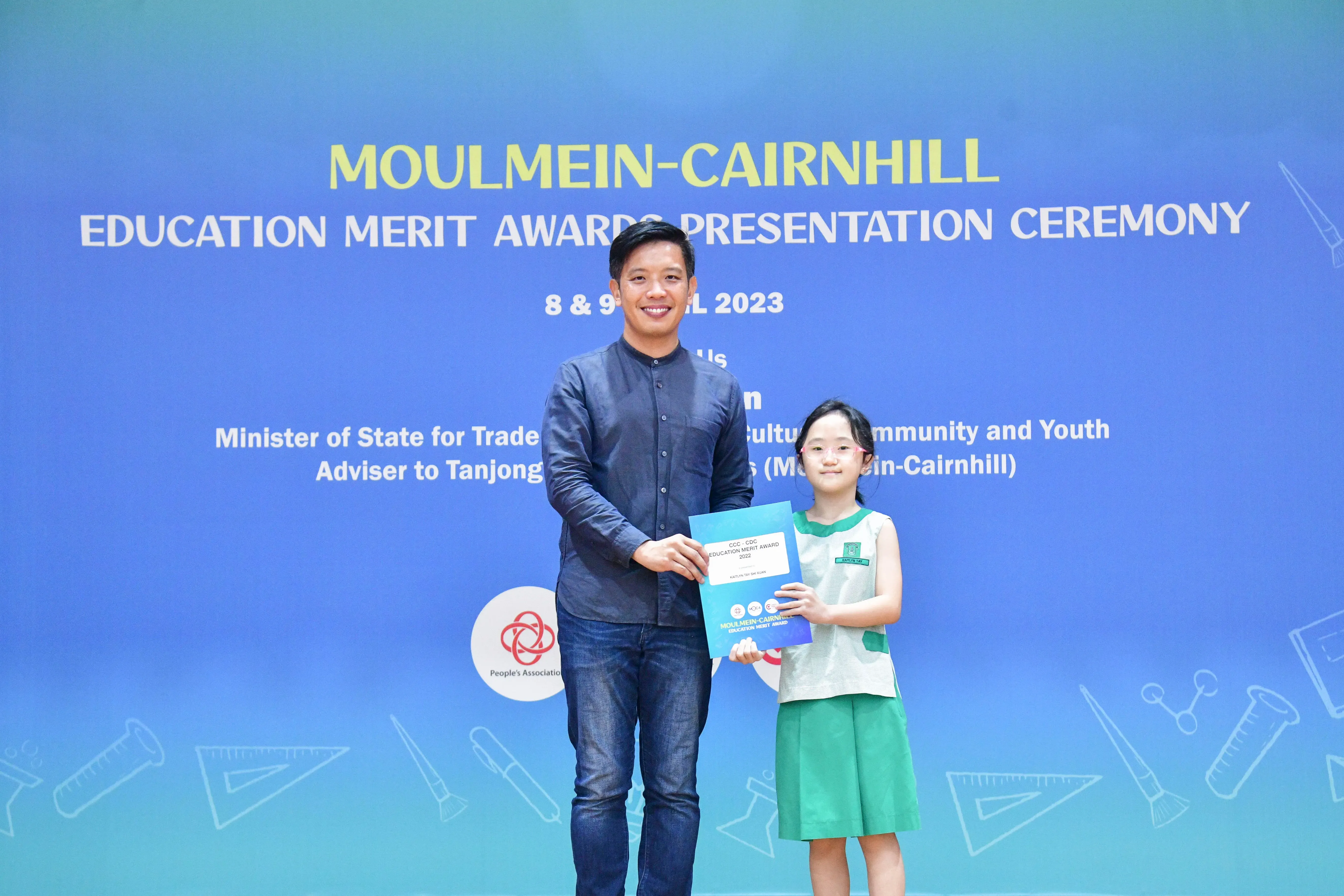 A man and a young girl hold a certificate together at the Moulmein-Cairnhill Education Merit Awards Ceremony 2023.