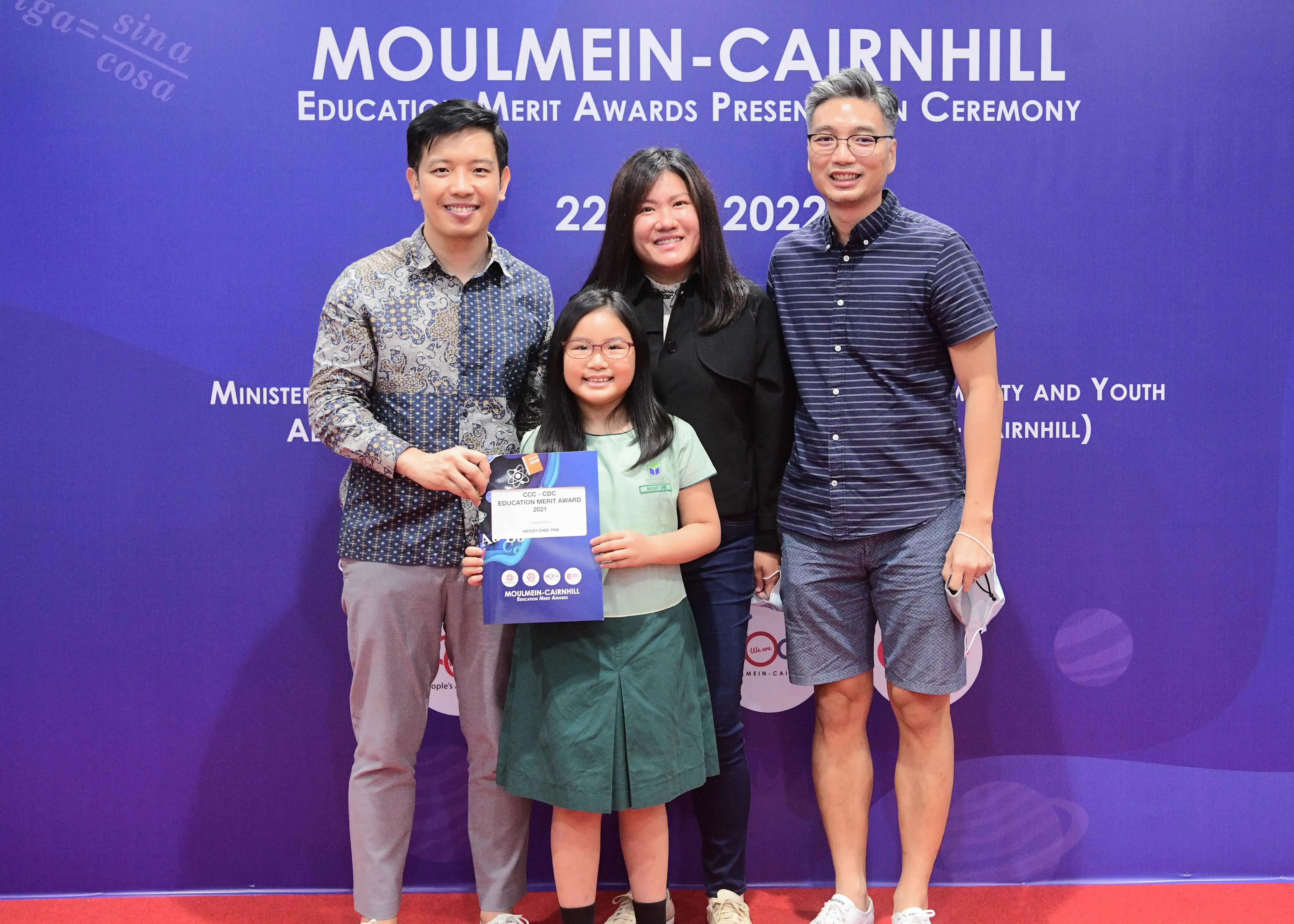 Three adults and a young girl holding an award certificate pose at the Moulmein-Cairnhill Education Merit Awards 2022.