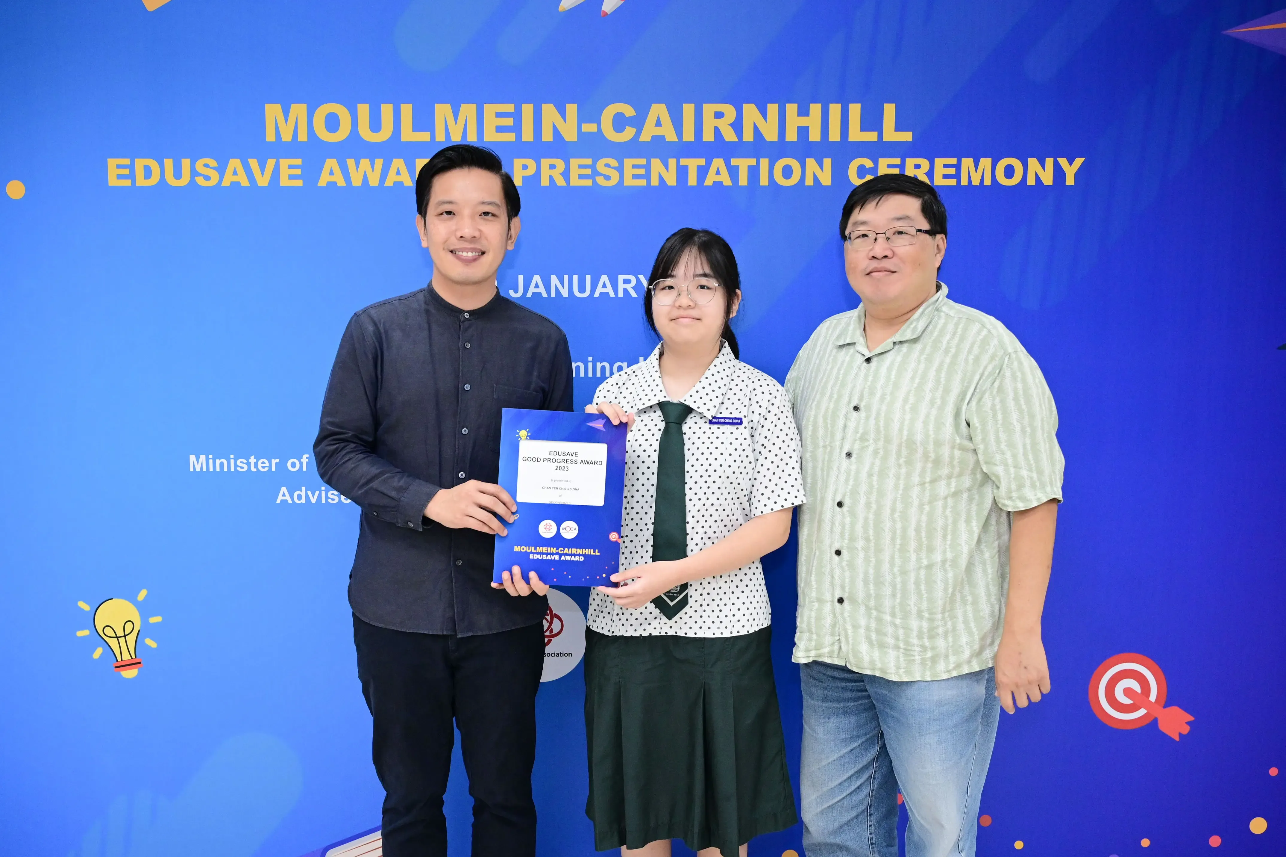Three people pose holding an Edusave award certificate at the Moulmein-Cairnhill Edusave Award Presentation Ceremony.