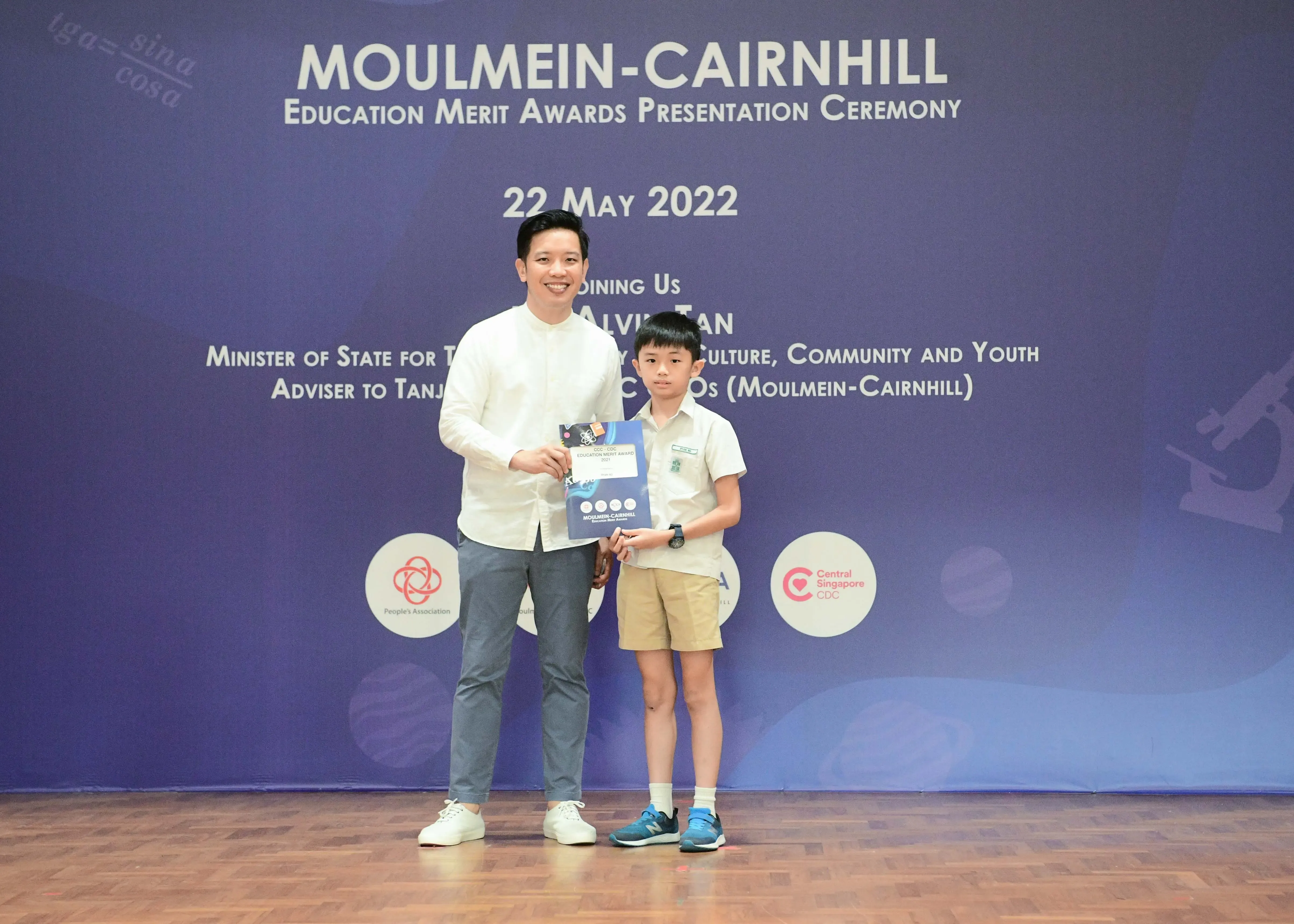 An adult and a young student hold an award certificate at the Moulmein-Cairnhill Education Merit Awards ceremony on 22 May 2022.