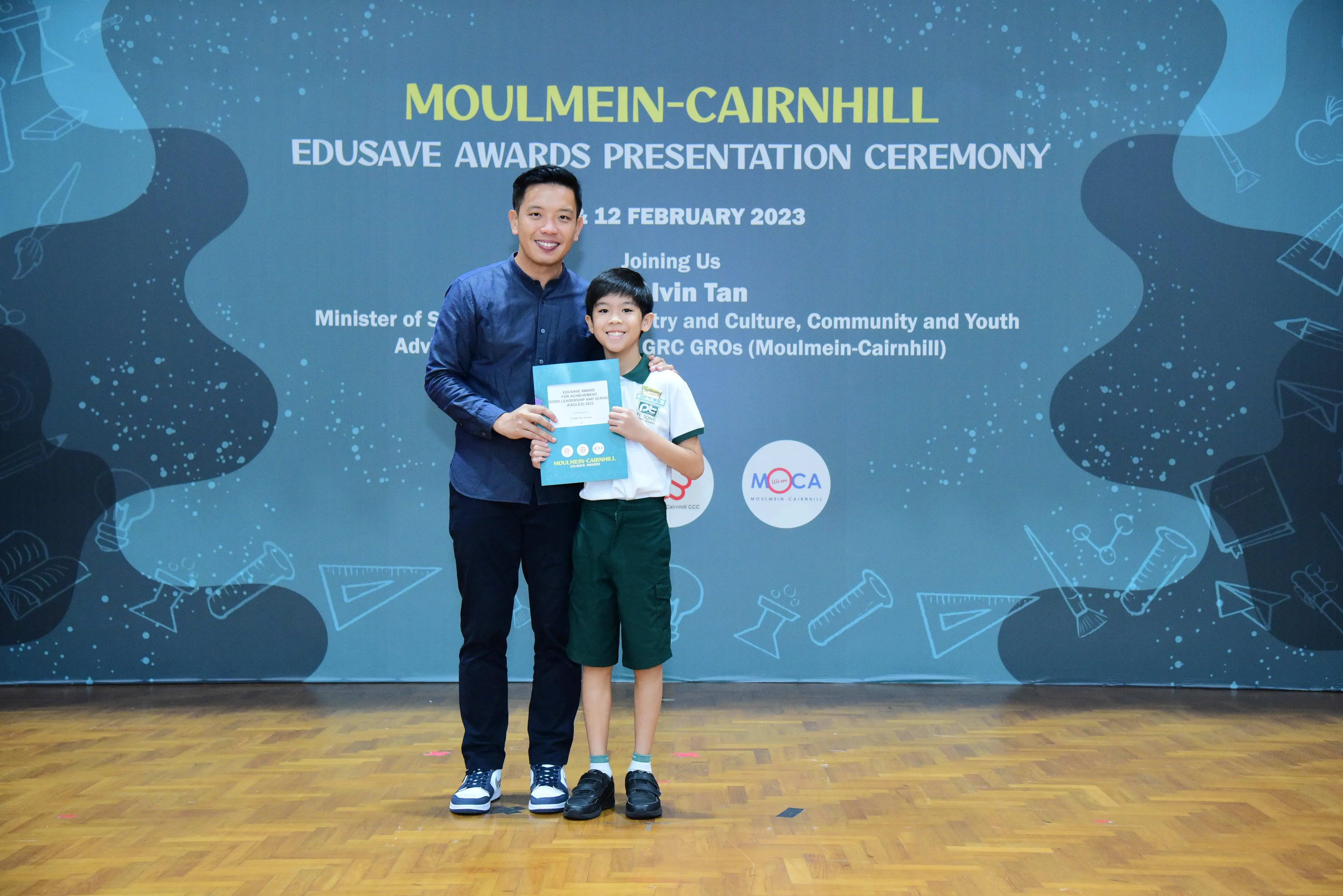A man and a young boy hold a certificate at the Moulmein-Cairnhill Edusave Awards Presentation Ceremony on 12 February 2023.