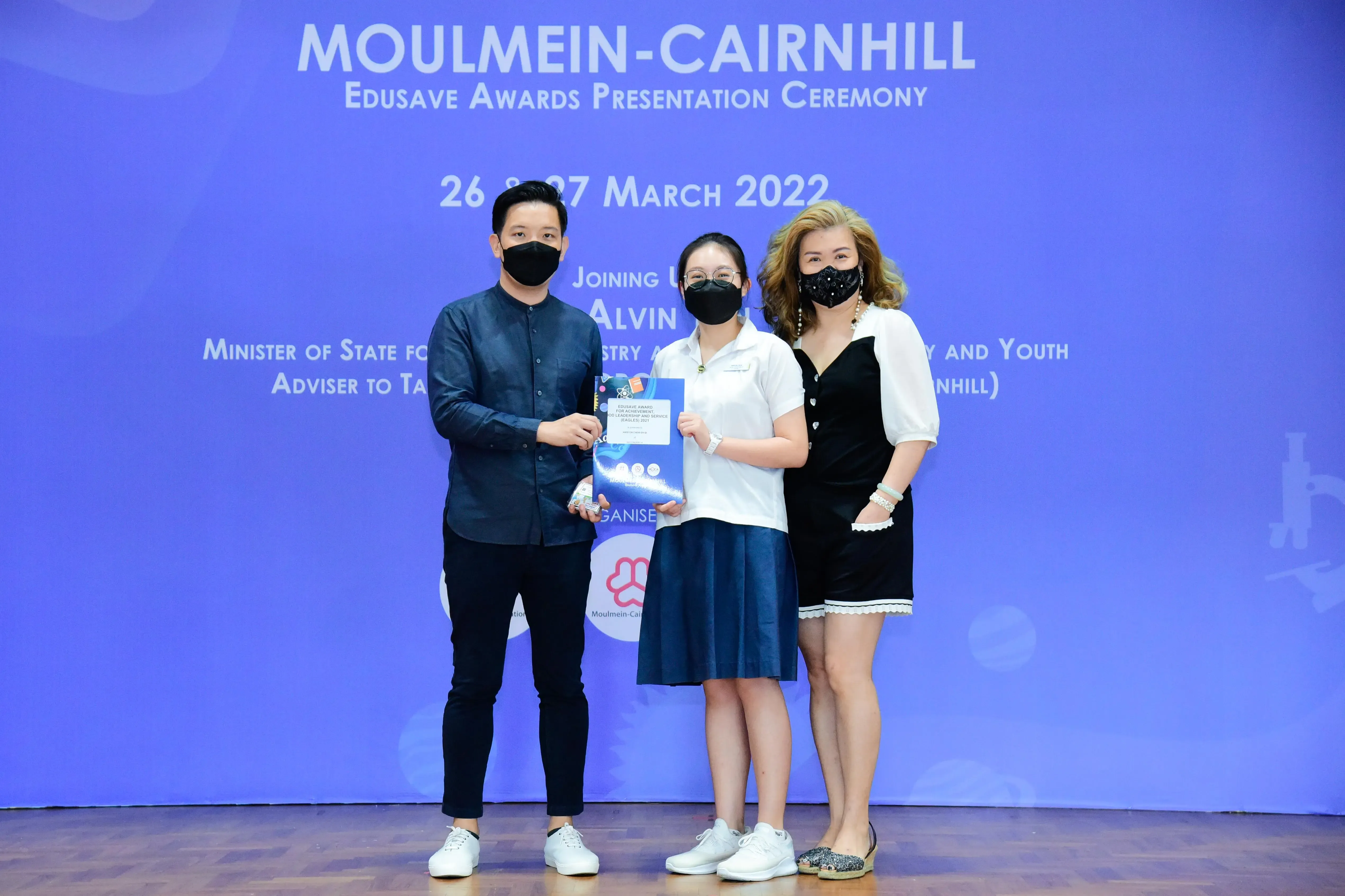 Three masked people pose at the Moulmein-Cairnhill Edusave Awards Presentation Ceremony on 26-27 March 2022.