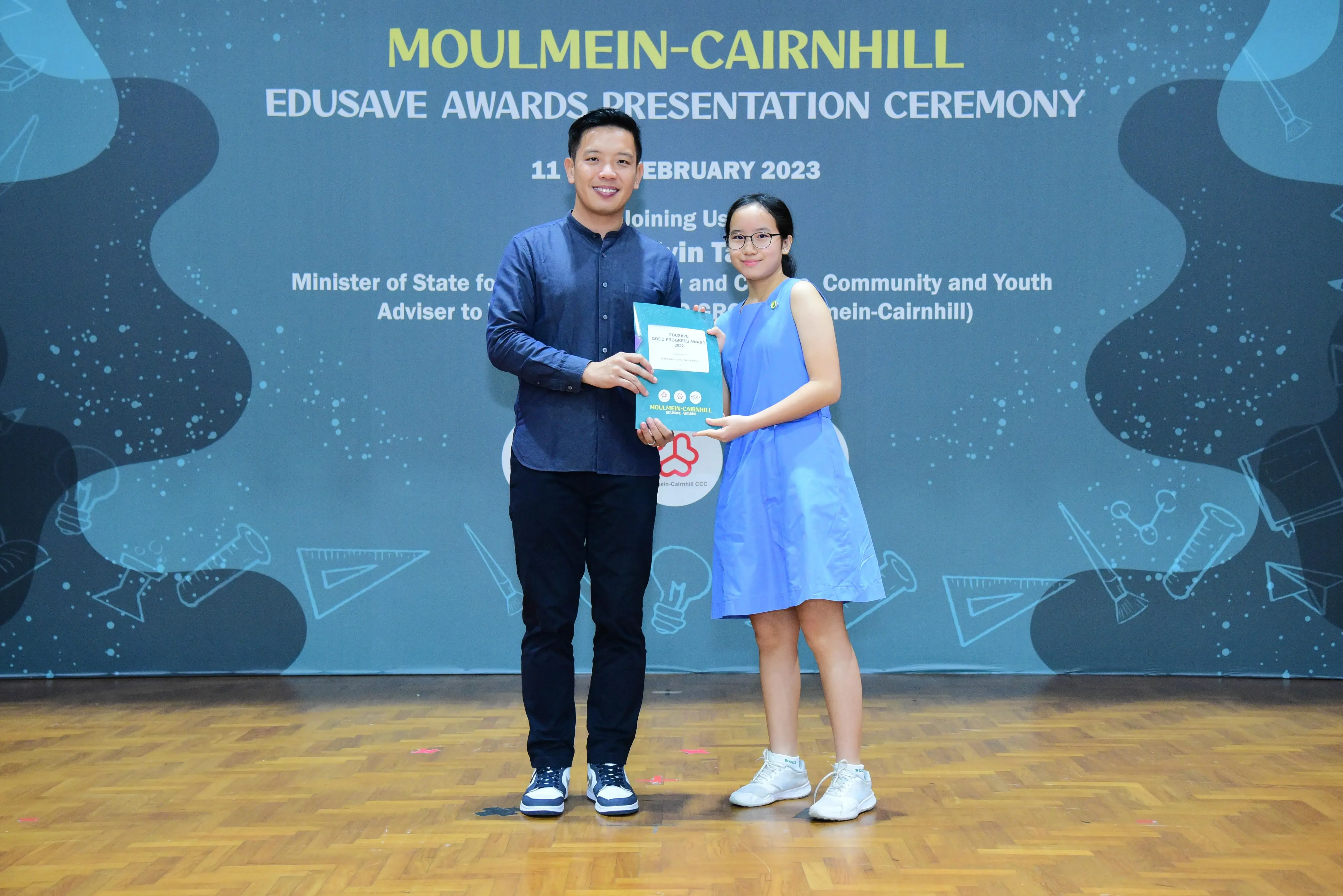 A man and a girl hold an award certificate at the Moulmein-Cairnhill Edusave Awards Presentation Ceremony 2023.
