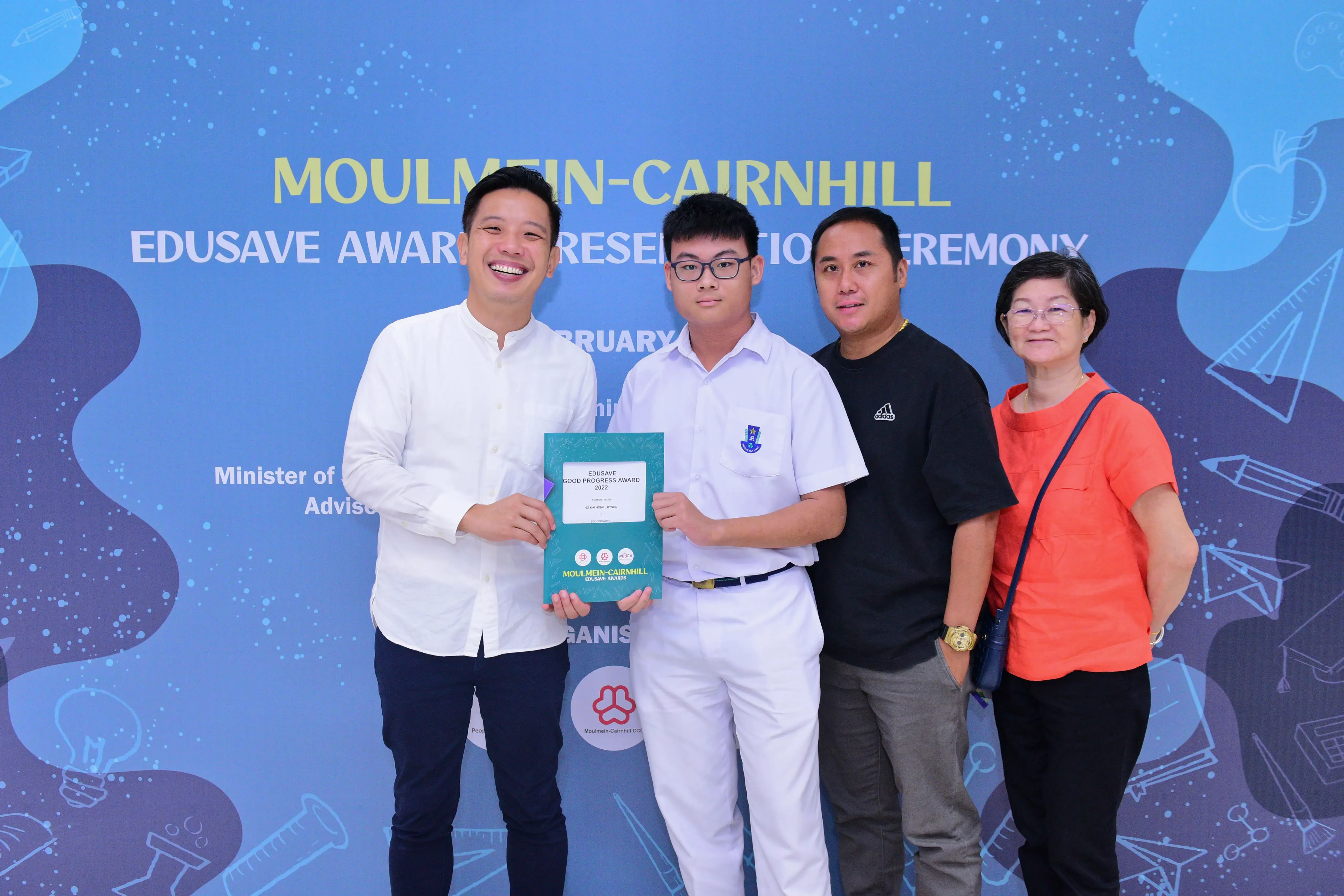 Four people pose at the Moulmein-Cairnhill Edusave Award Presentation Ceremony, with a student holding a certificate.